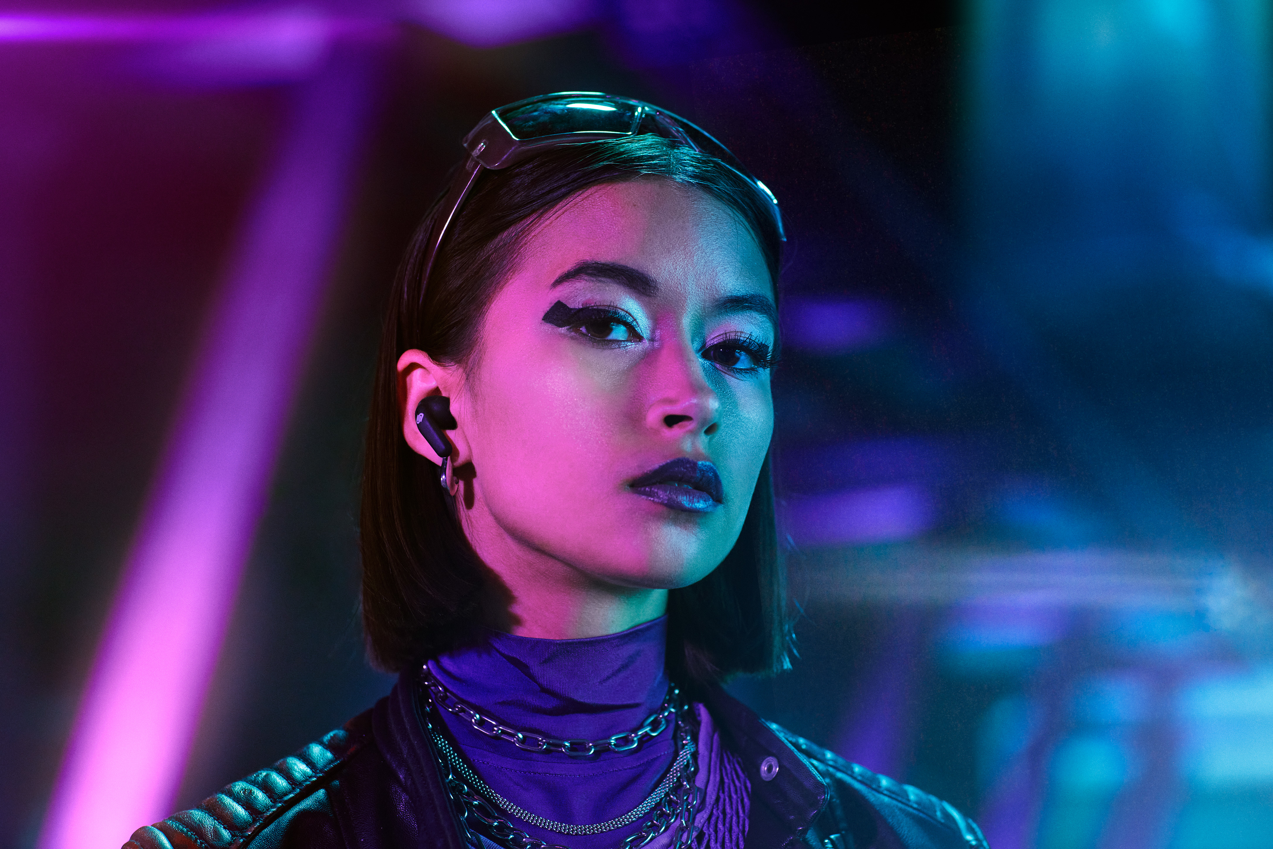 Kobieta w słuchawkach, patrząca w kamerę, fajne oświetlenie.