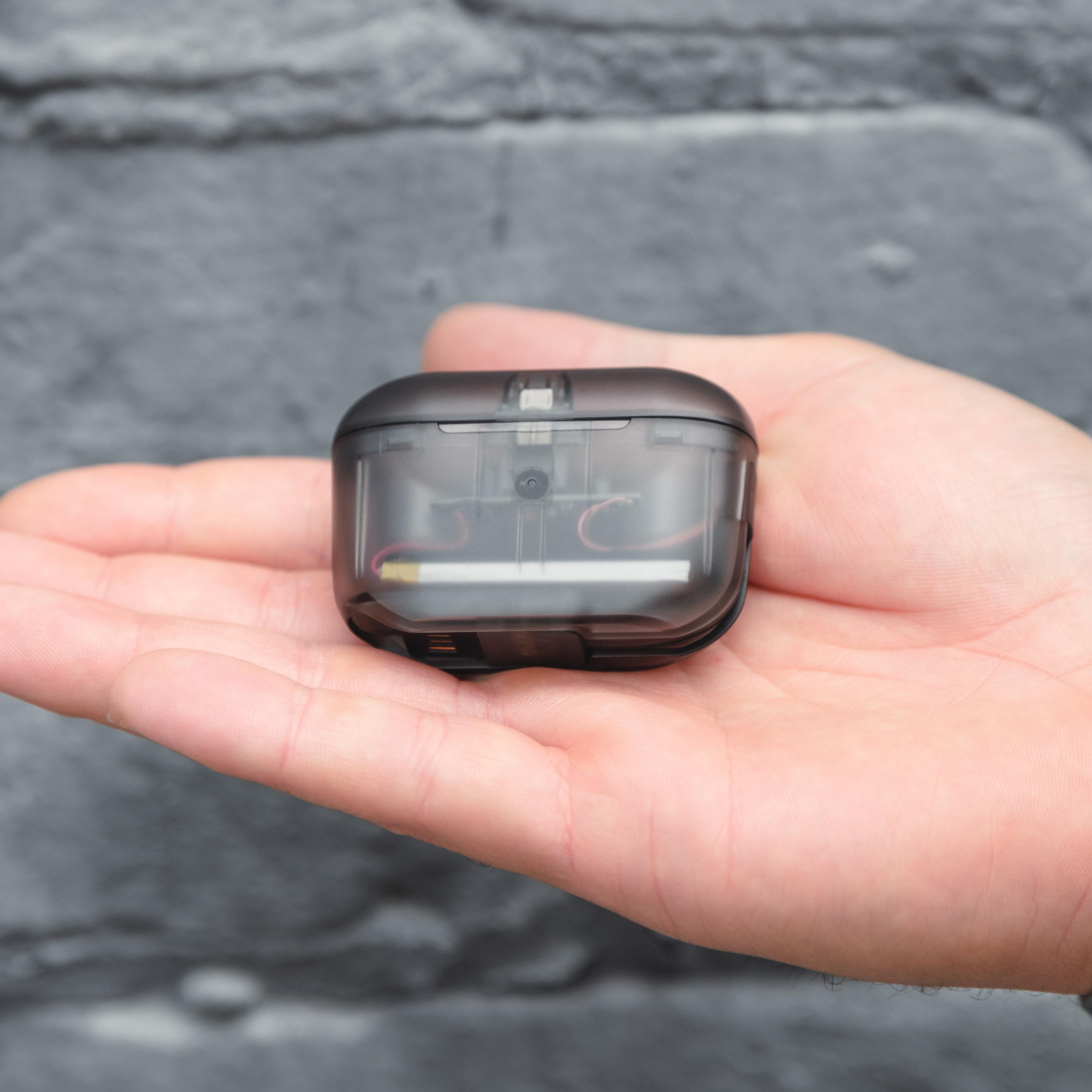 Hand hält eine kleine, schwarze, transparente Hülle. Hülle enthält eine Batterie und Drähte.