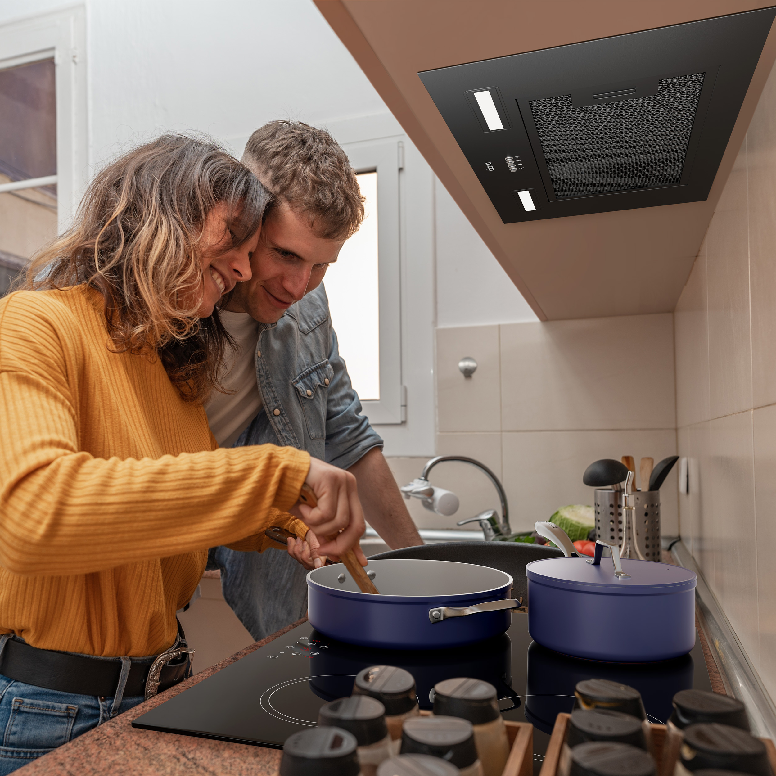 Koppel dat kookt in een keuken met een fornuis, potten en een afzuigkap.