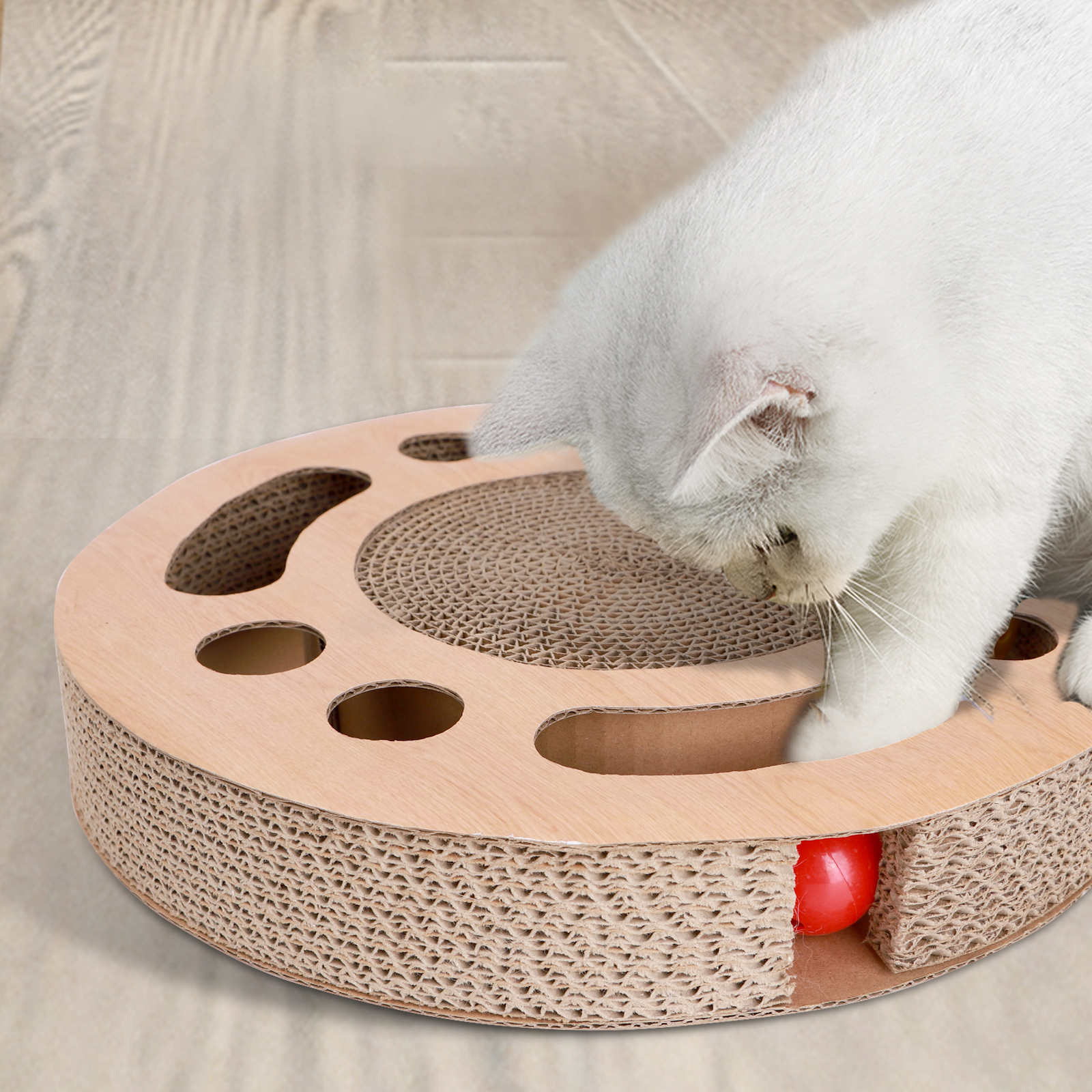 Gato blanco jugando con un rascador. El rascador tiene una bola roja.