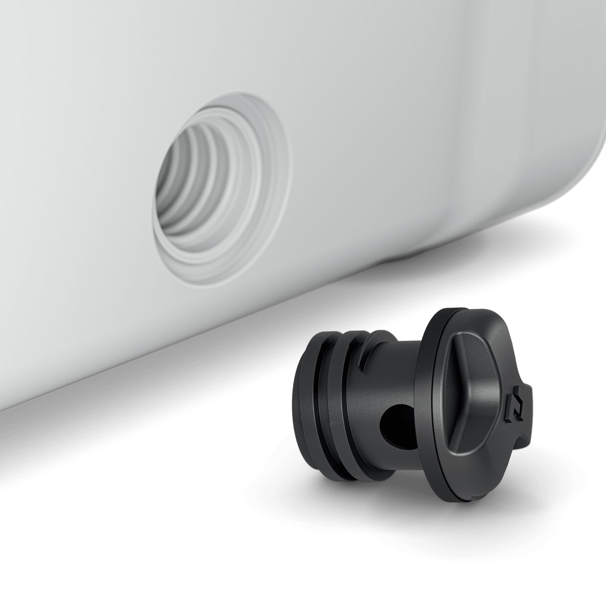 Een zwarte plastic plug, bij een wit oppervlak met een gat, tegen een witte achtergrond.