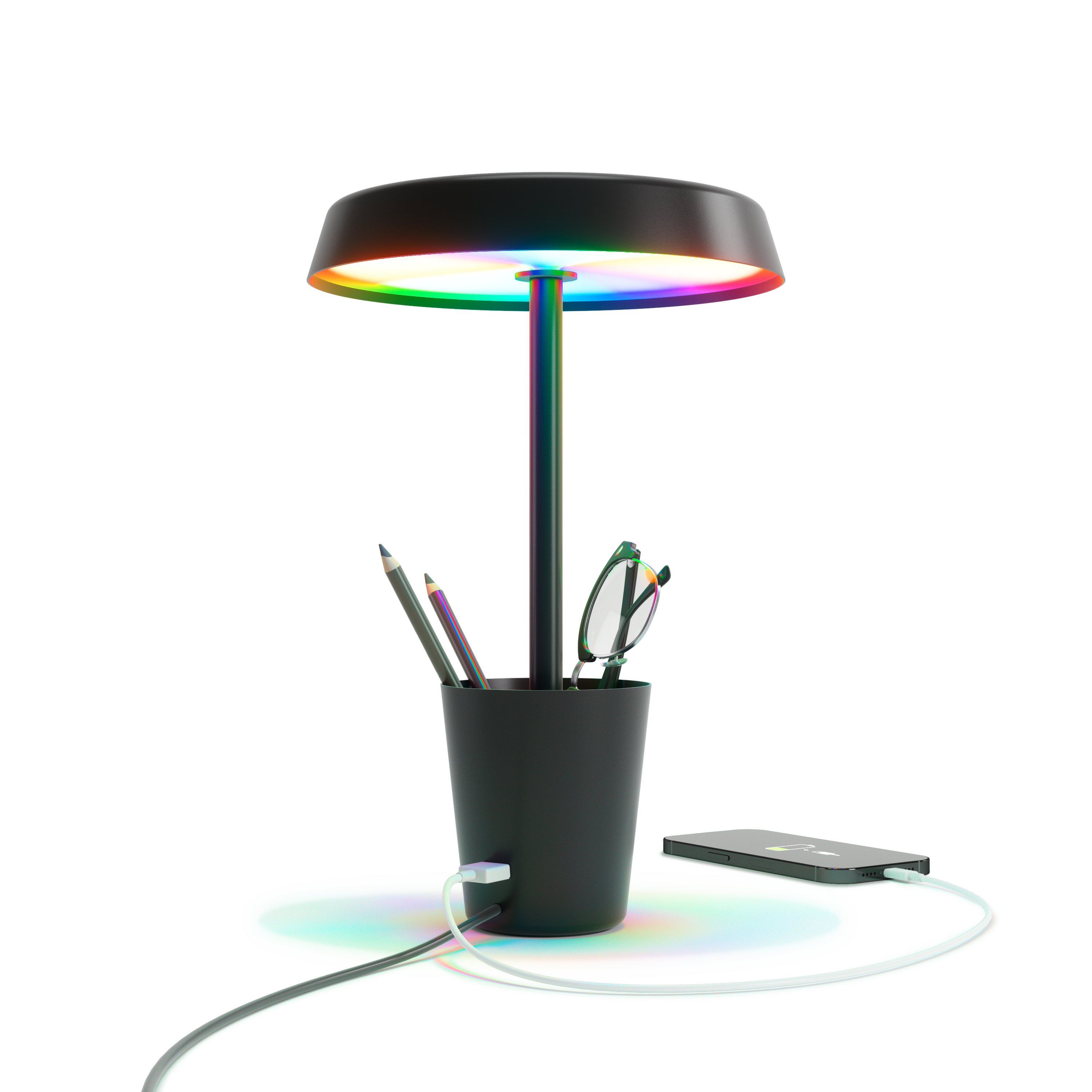 Una lampada nera con un anello di luce colorato, matite, occhiali e un telefono in carica. Tutto su una superficie bianca.