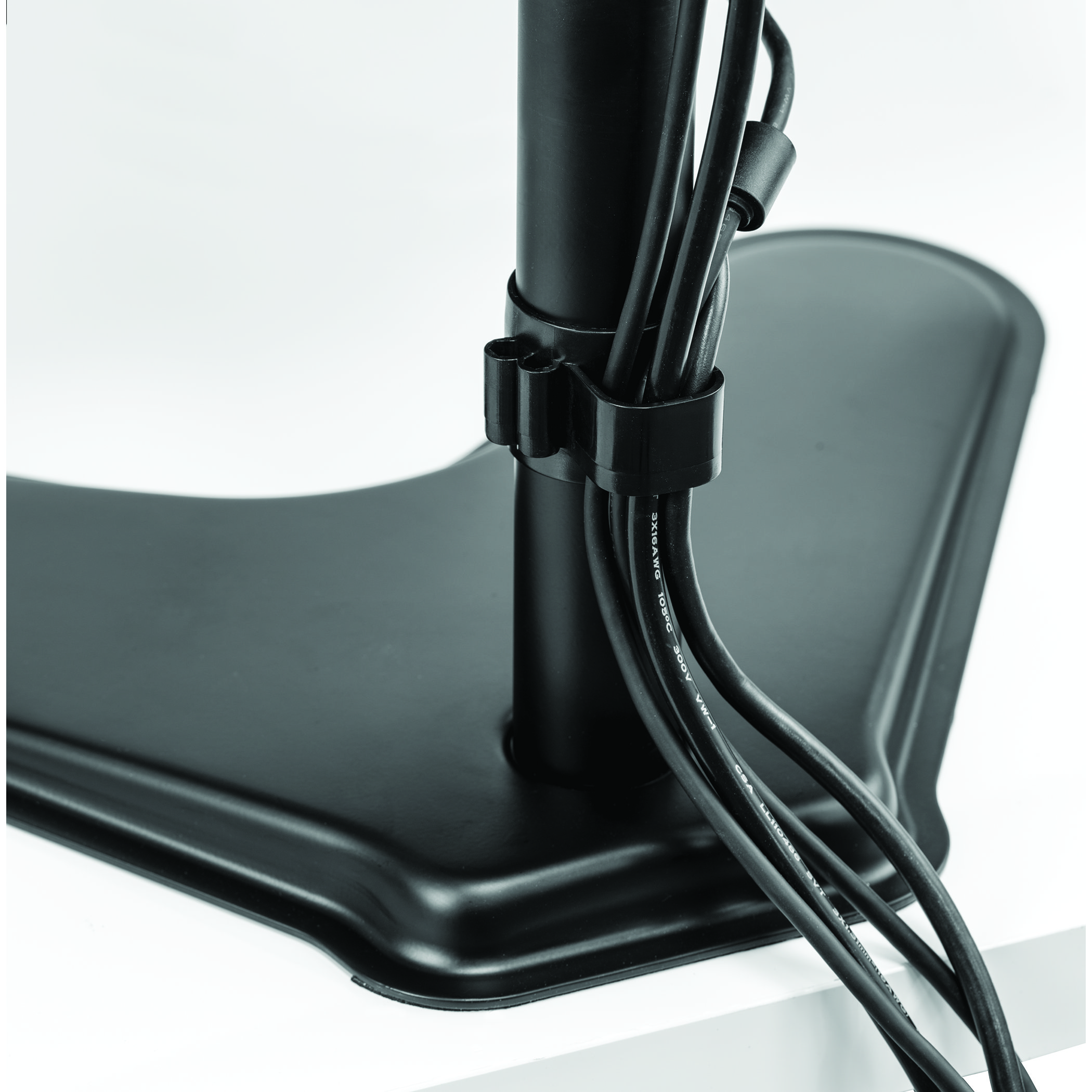 Black monitor stand base with cables attached. Cables are secured with a black clip.