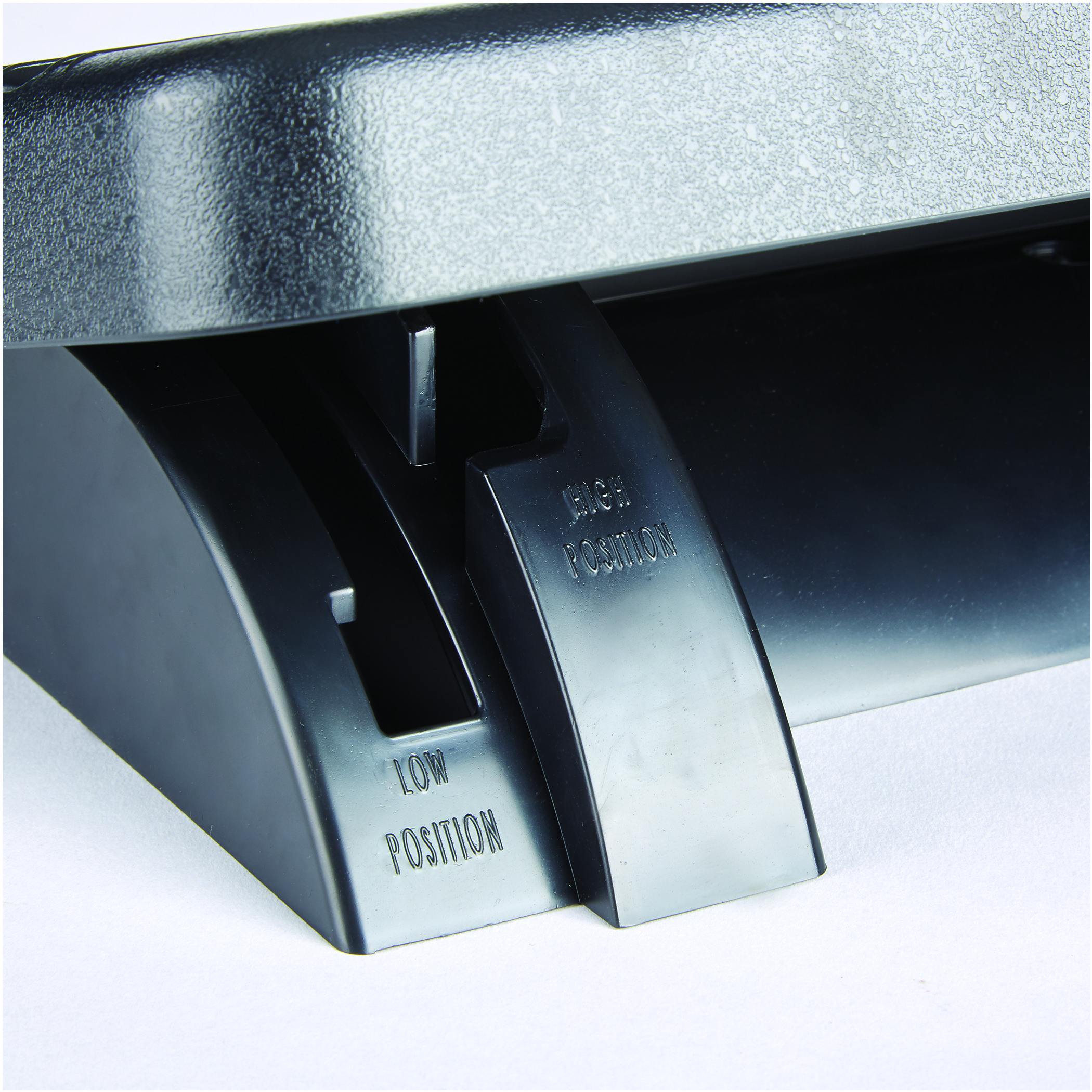 Czarny, regulowany podnóżek z etykietami 'HIGH POSITION' i 'LOW POSITION'. Z bliska.