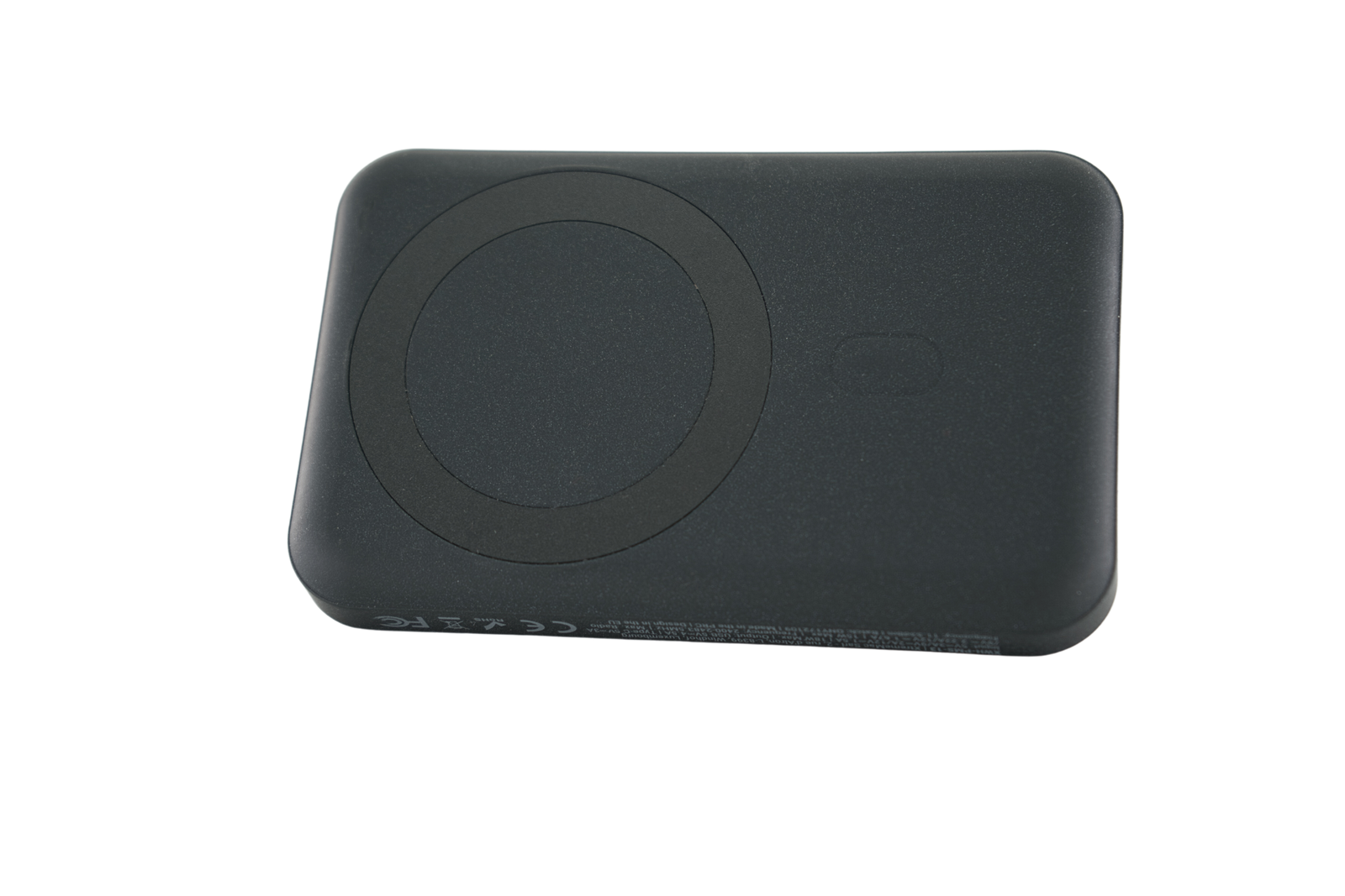 Zwart draadloos oplaadpad met een cirkelvormige inkeping. Donker oppervlak, schuine opname.