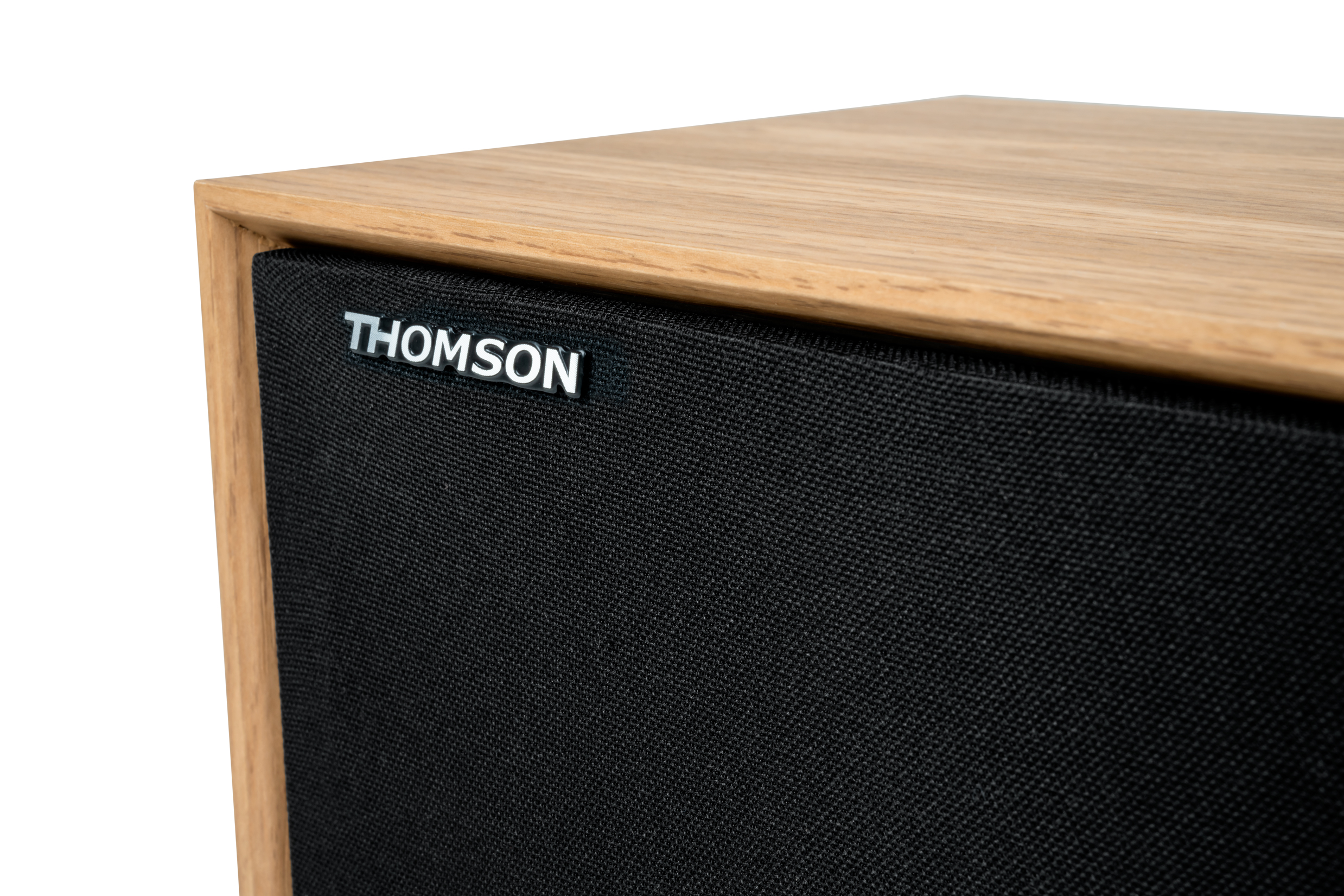 Zbliżenie drewnianego głośnika. Głośnik ma czarną tkaninę i srebrne logo "THOMSON".