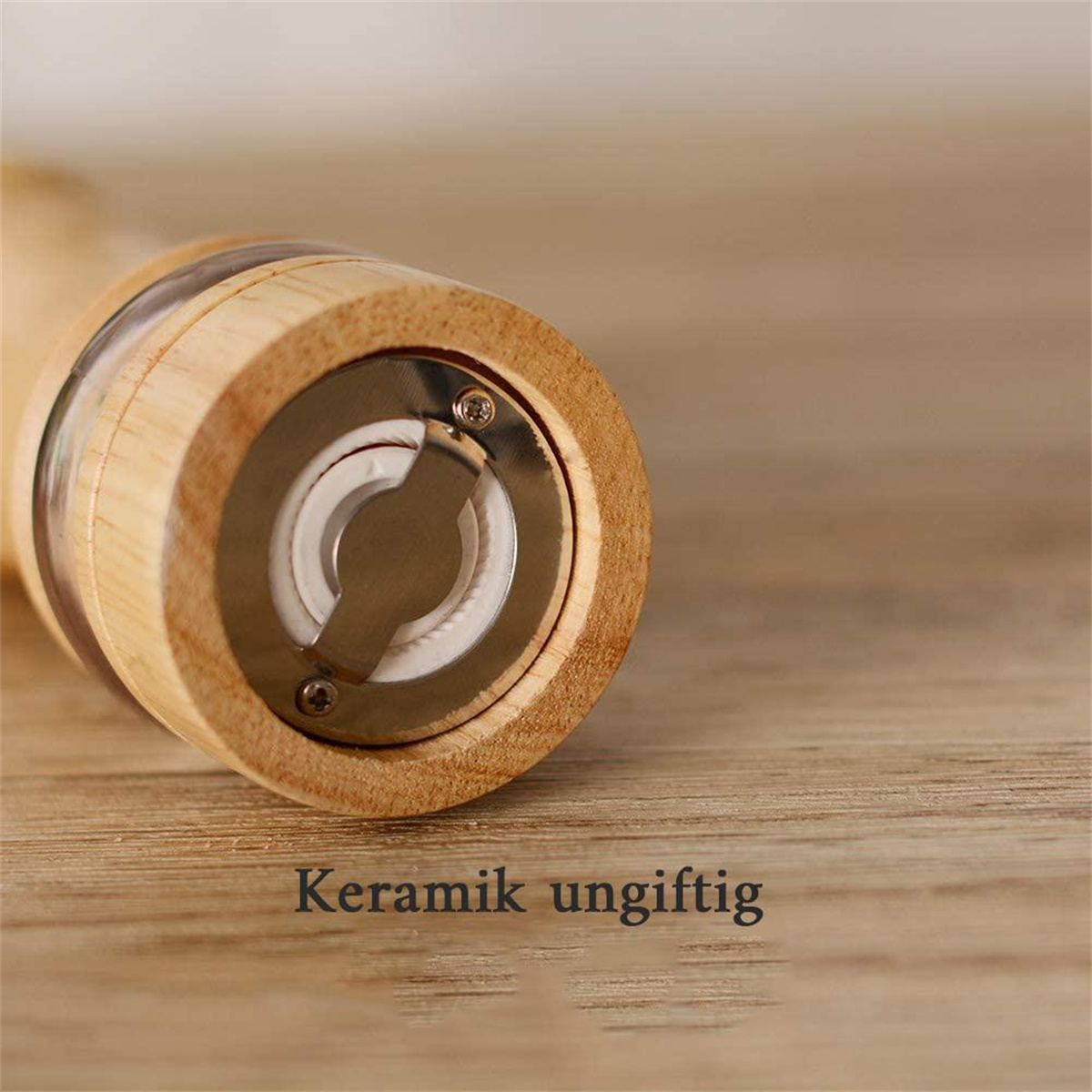 Nahaufnahme eines Holzpfeffermühlen mit Metallteilen, Text 'Keramik ungiftig'.