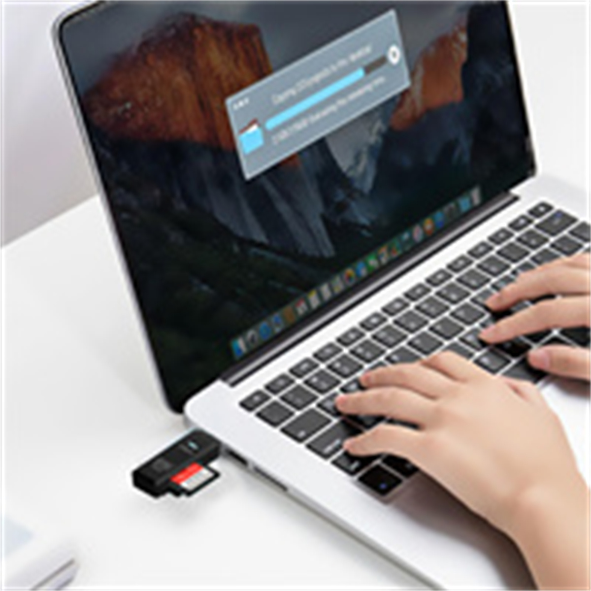 Eine Person benutzt einen Laptop, ein schwarzer Kartenleser ist angeschlossen und überträgt Daten.