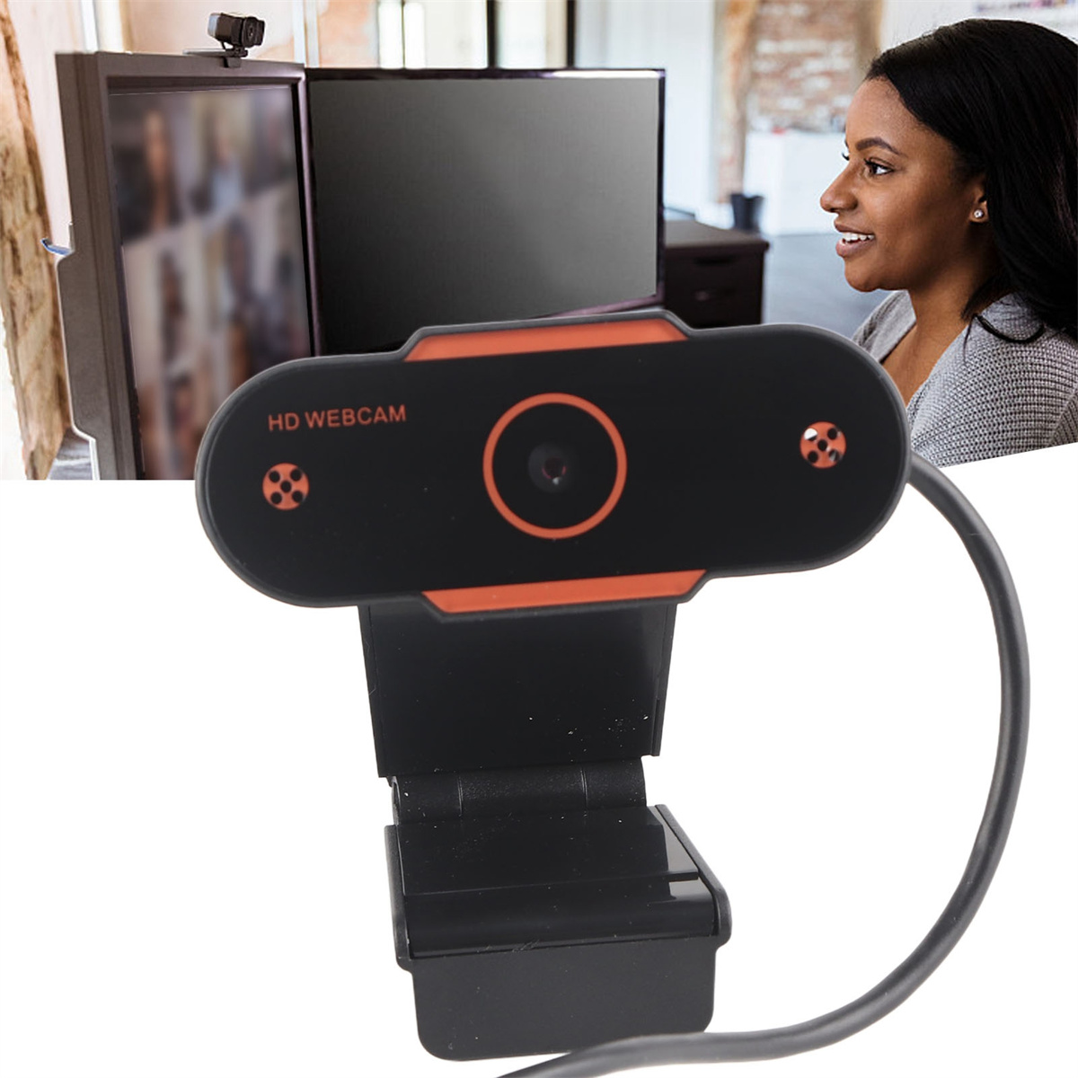 Webcam mit lächelnder Frau, die vor mehreren Computerbildschirmen sitzt. Webcam hat orangefarbene Akzente.