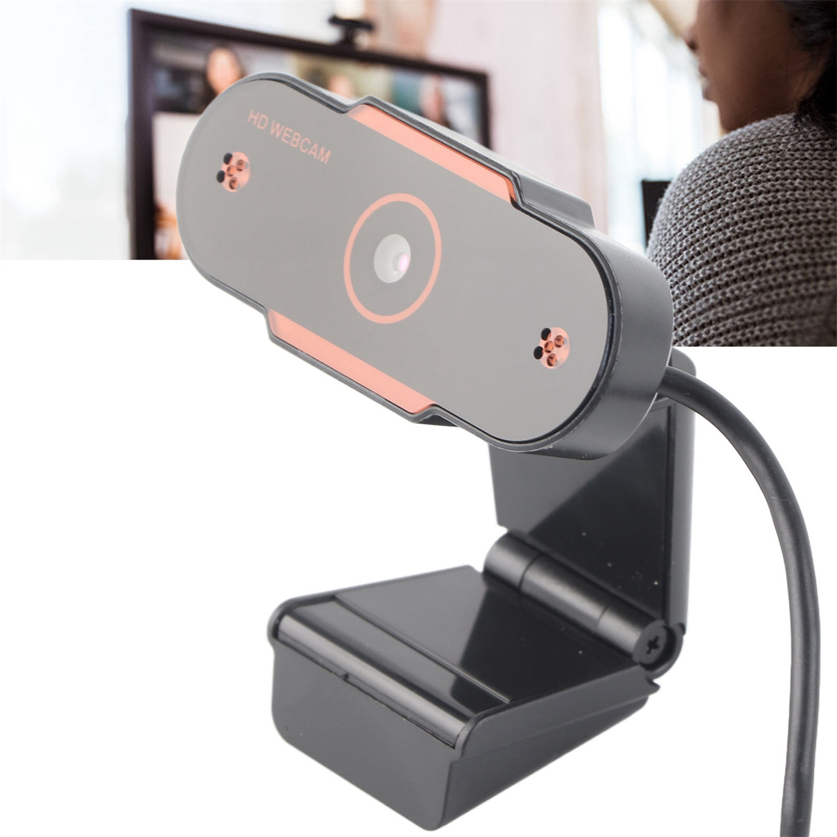 Eine schwarze Webcam mit rotem Akzent, montiert auf einem Ständer, mit einer verschwommenen Person im Hintergrund.