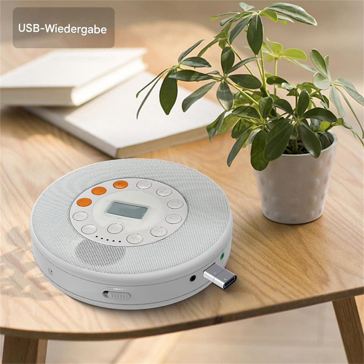 Weißer tragbarer CD-Player mit orangen Knöpfen und einem USB-Anschluss auf einem Holztisch.