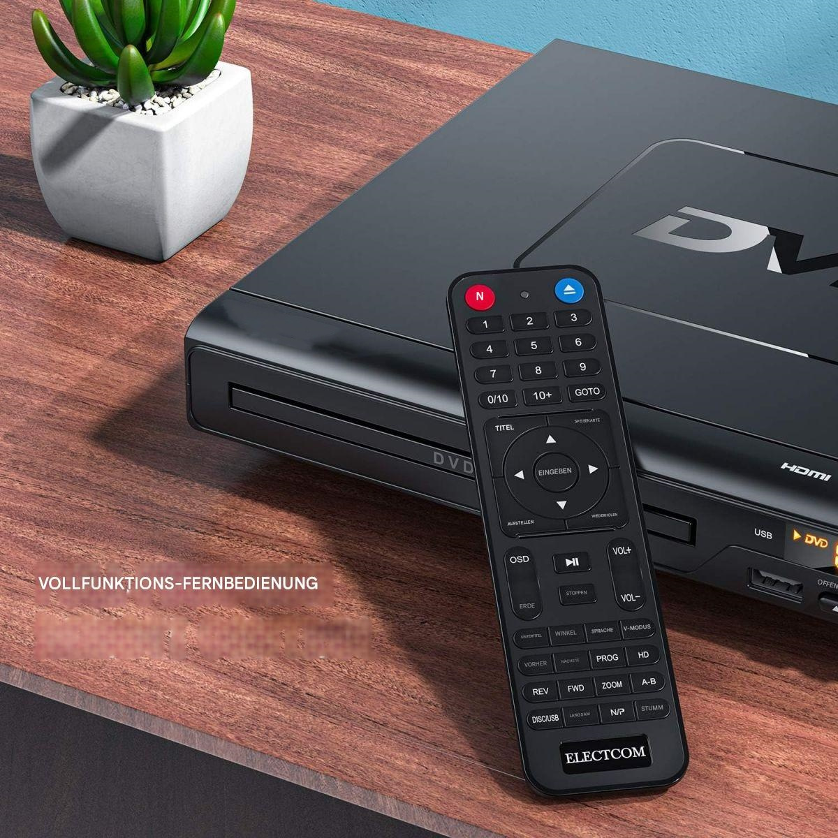 DVD-Player und Fernbedienung auf Holz, mit Topfpflanze im Hintergrund.