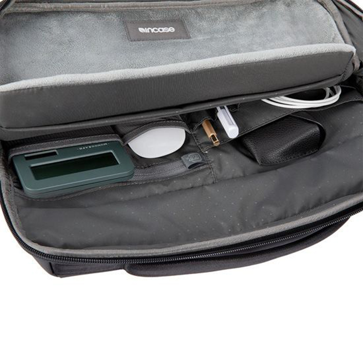 Bolsa abierta con portátil, ratón, bolígrafo y otros objetos visibles. Una bolsa para portátil.