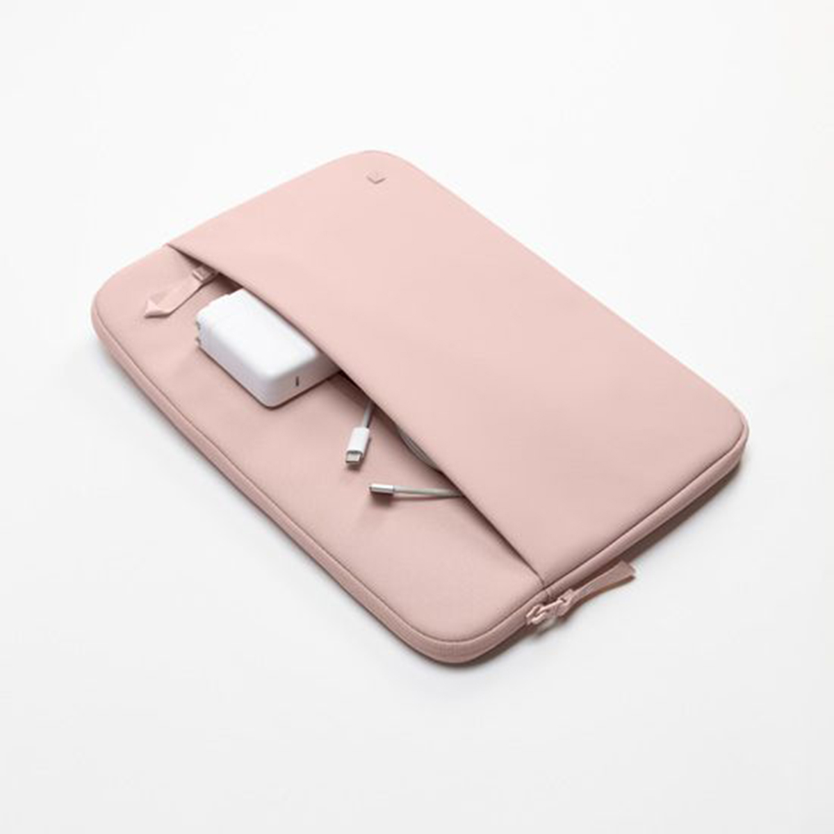Funda rosa para portátil con un cargador y cable blancos dentro, sobre una superficie blanca.