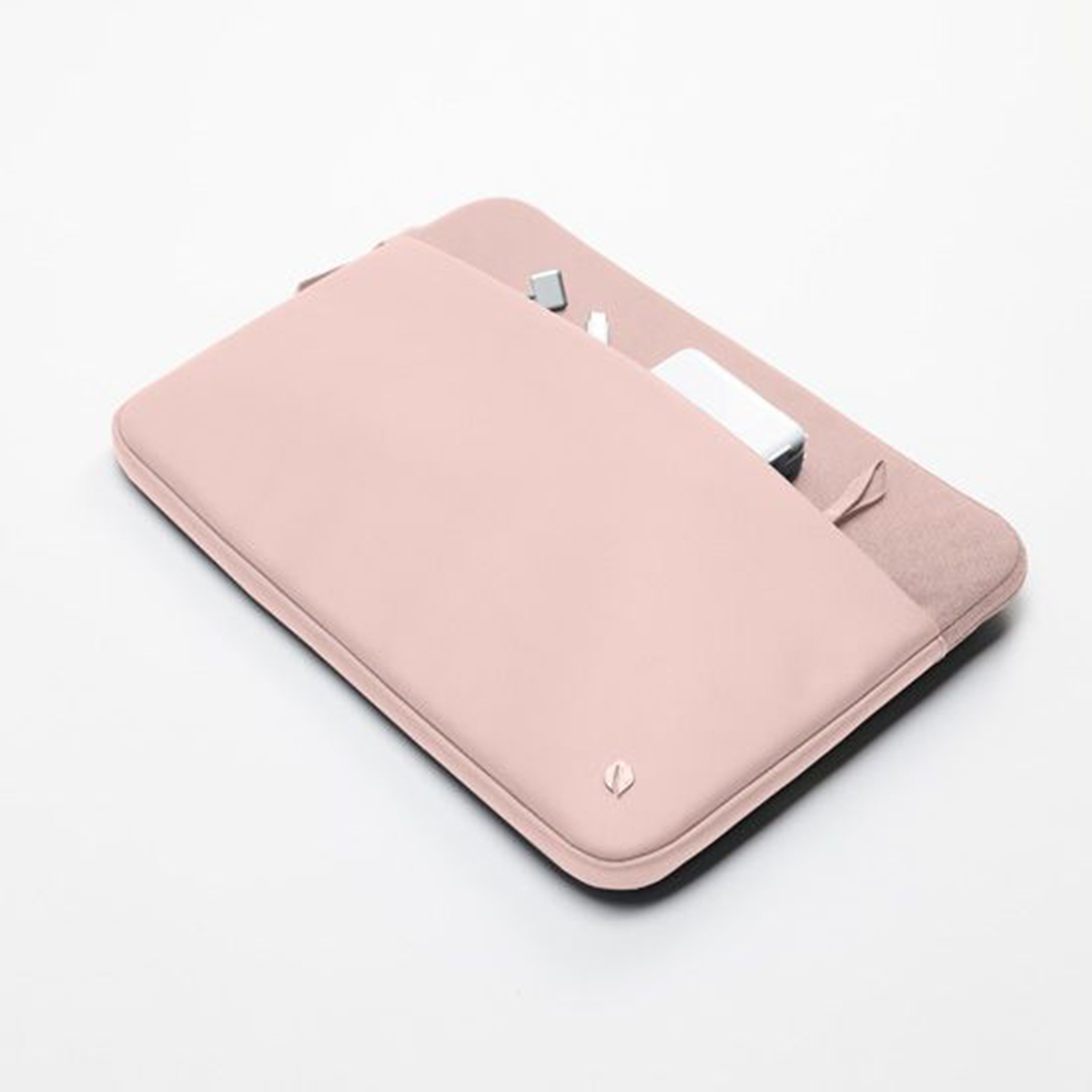 Una funda rosa para tableta con una parte abierta que revela un bloque de carga blanco y otros artículos.