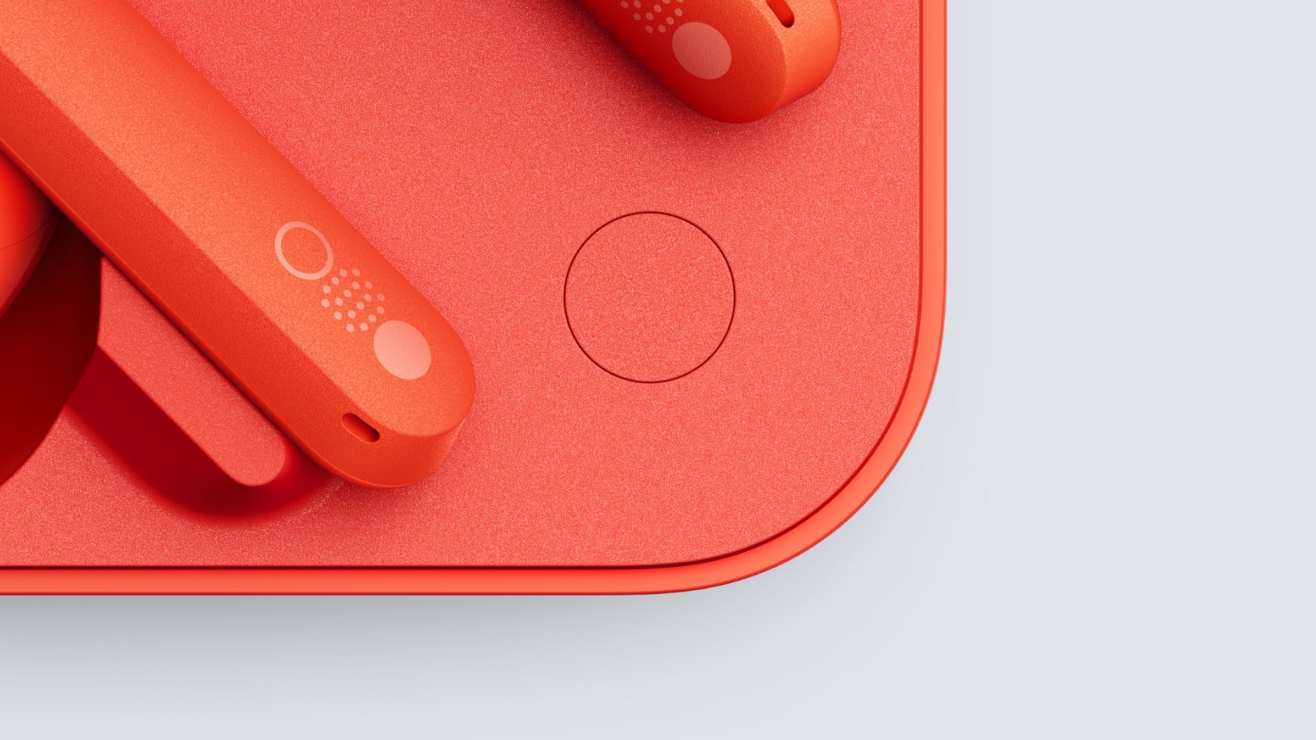 Primer plano de auriculares inalámbricos naranjas y base de carga. Fondo blanco.