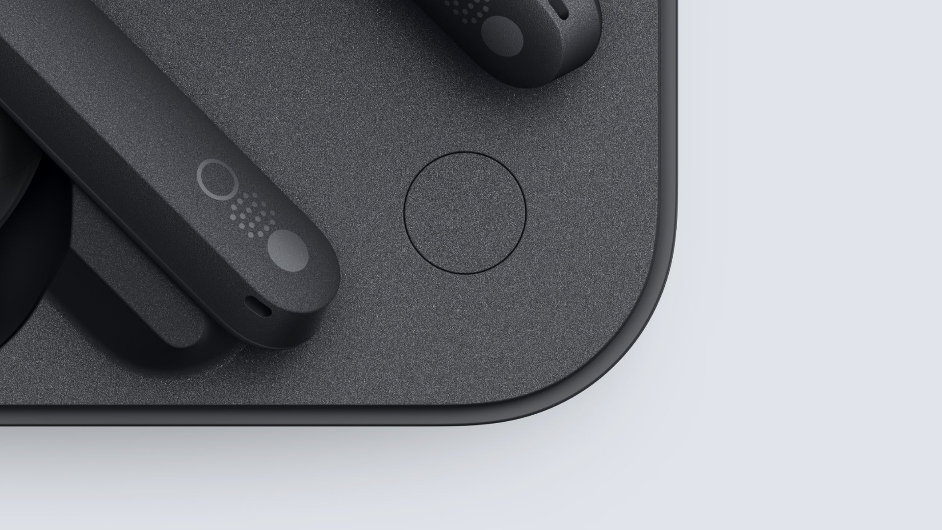 Czarne słuchawki bezprzewodowe na podkładce ładującej. Białe tło.