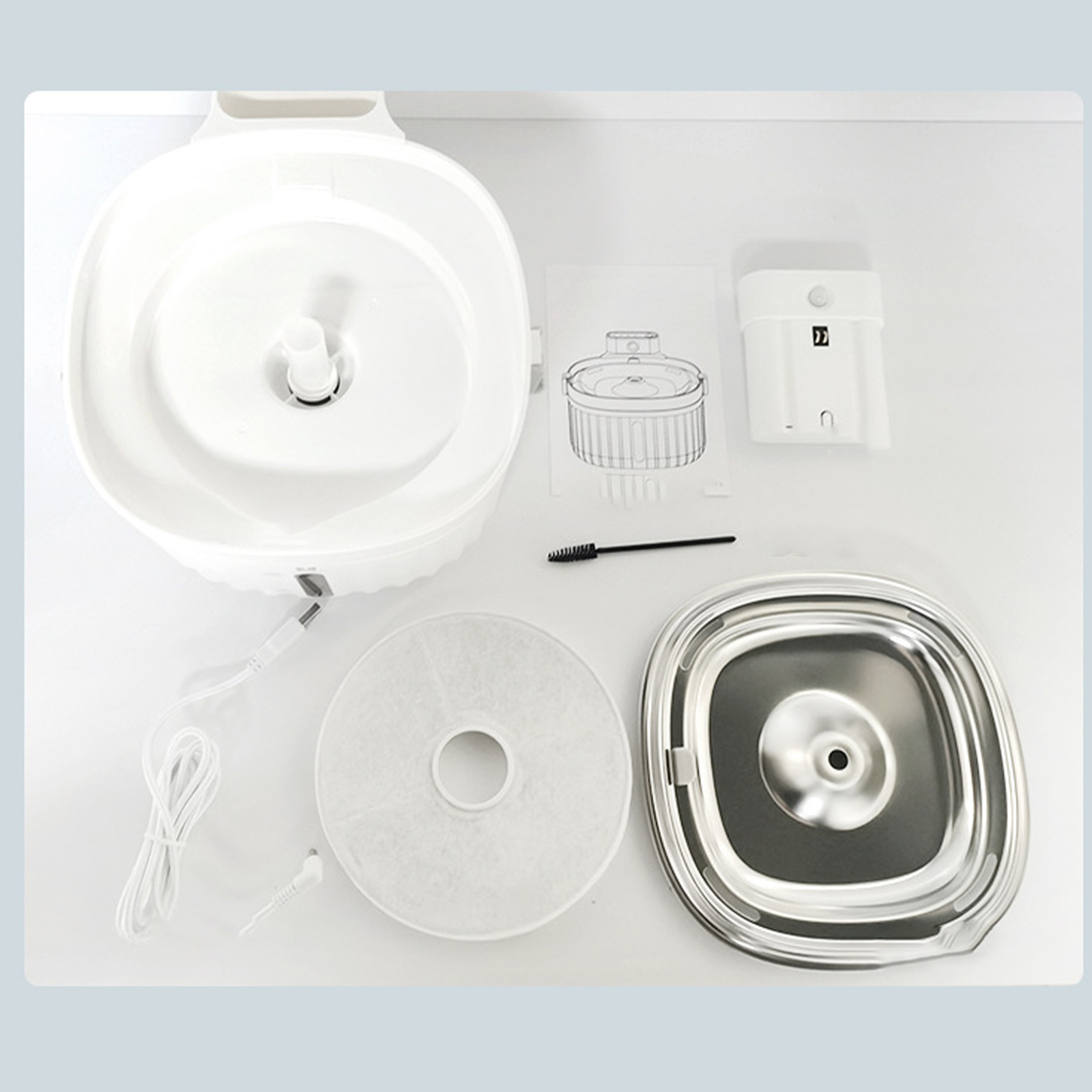 Weißer Haustier-Trinkbrunnen mit Komponenten: Filter, Bürste und Schüssel. Draufsicht.