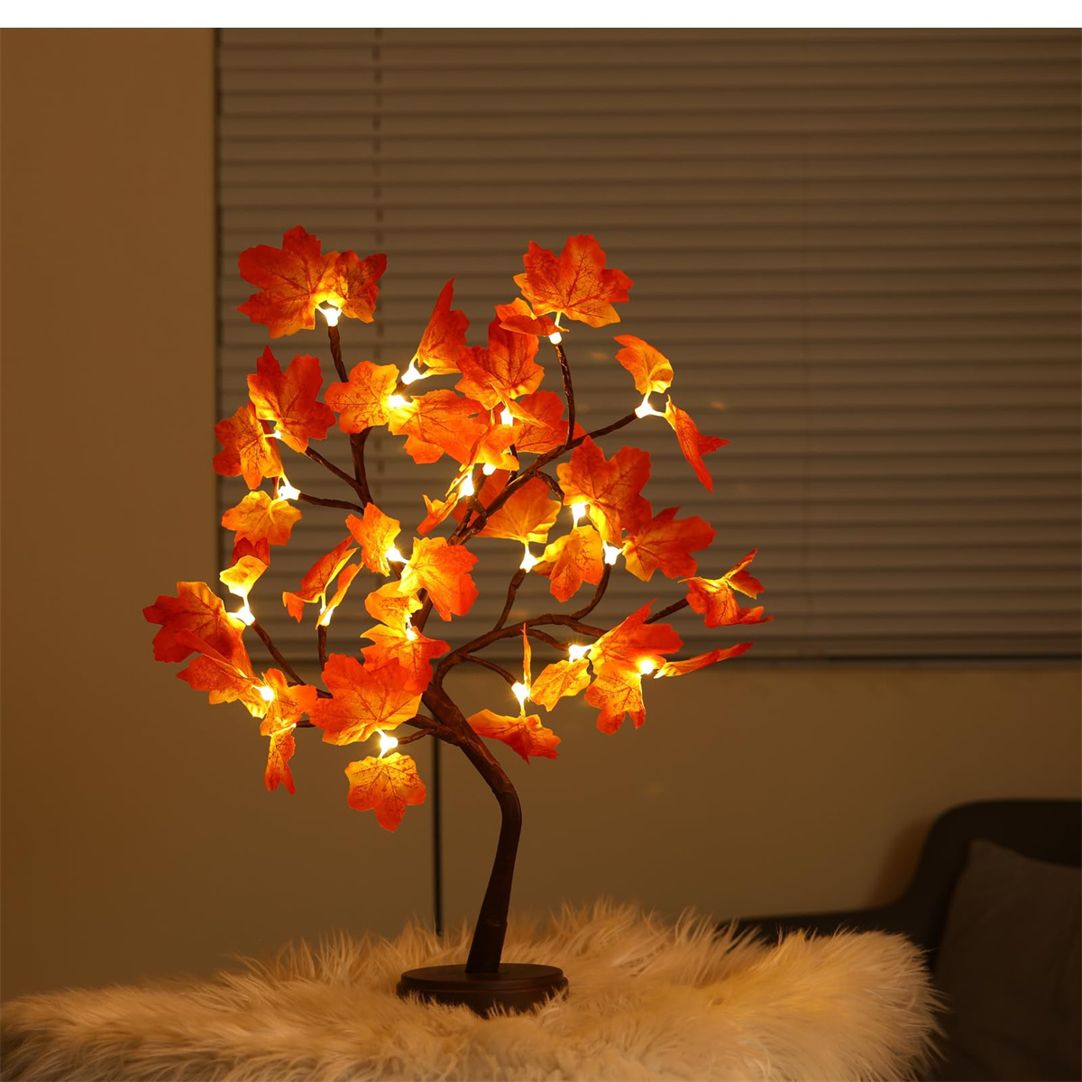 Dekorative LED-Baumlampe mit orangefarbenen Blättern und braunen Zweigen. Auf einer Oberfläche platziert.