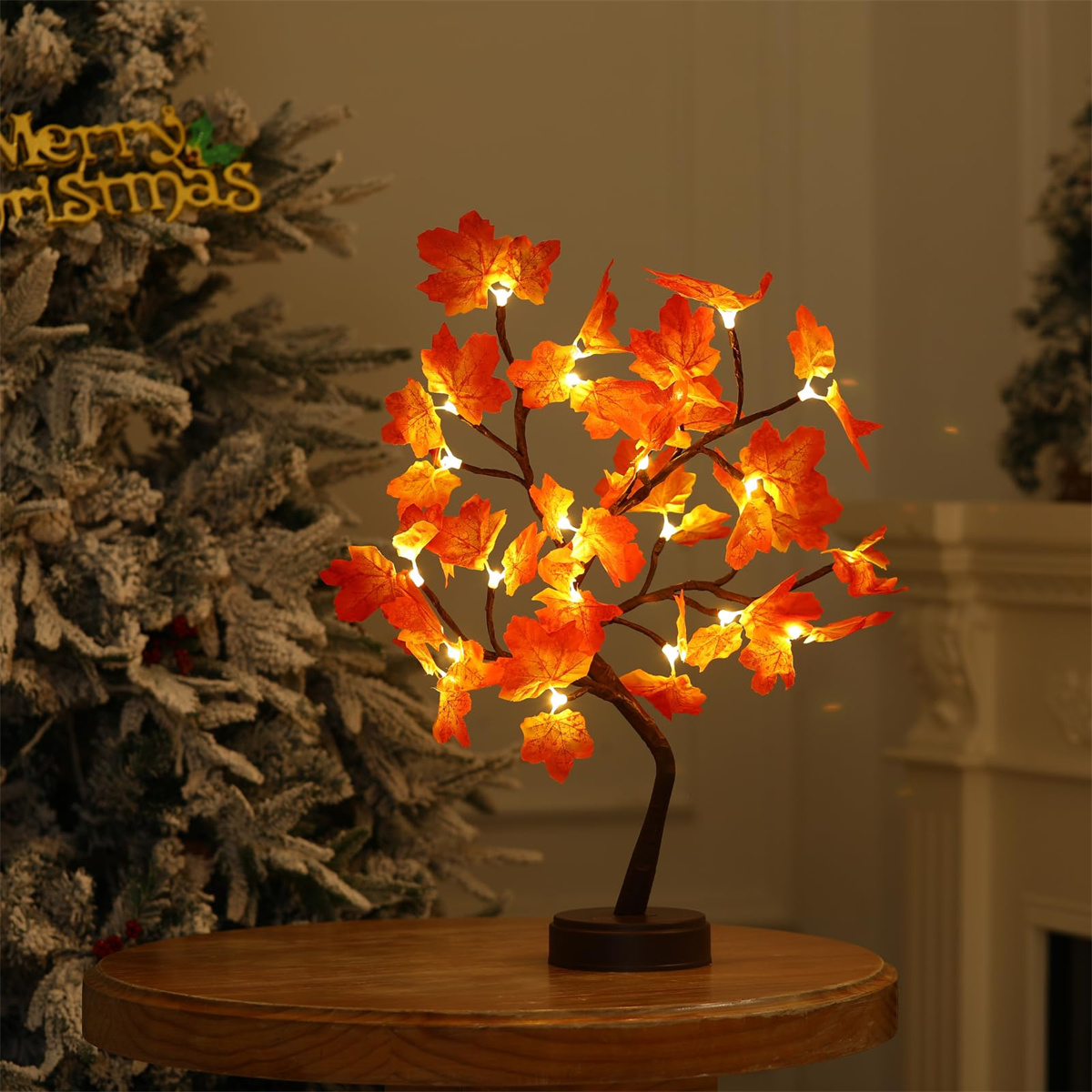 Ein dekorativer Baum im Herbststil mit orangefarbenen Blättern und Lichtern auf einem Holztisch. Weihnachtsbaum im Hintergrund.