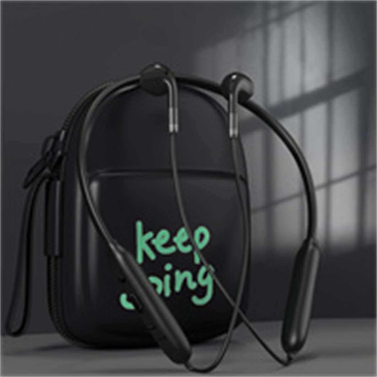 Schwarze Nackenbügel-Kopfhörer mit einem Etui. Auf dem Etui steht Keep Going.