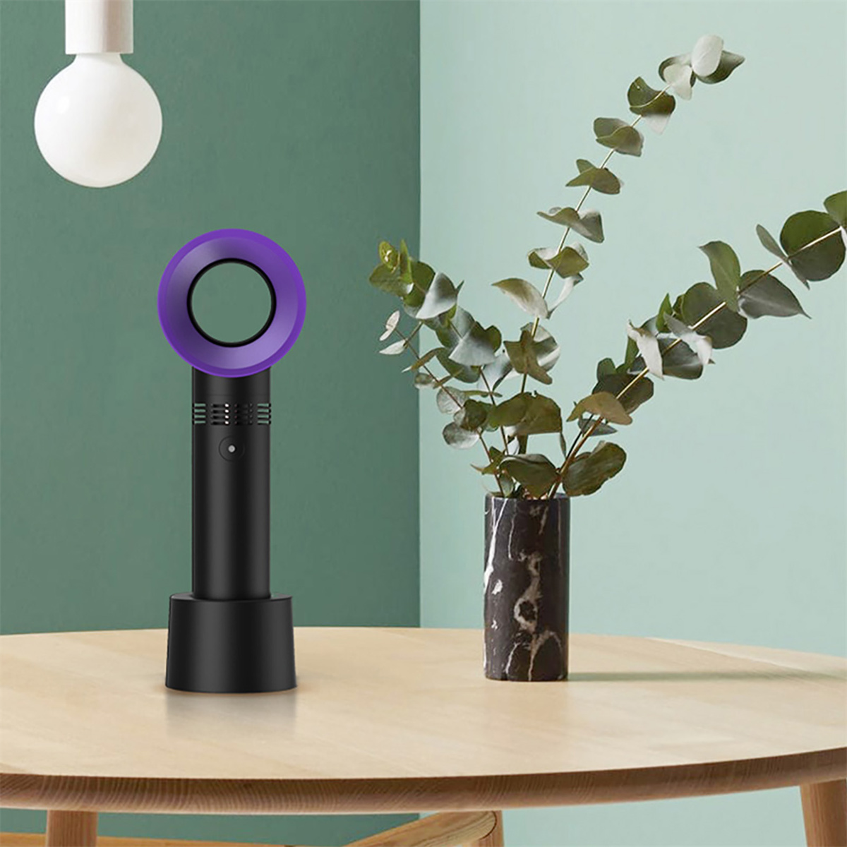 Schwarzer und lila blattloser Ventilator auf einem Holztisch. Rechts eine Vase mit grünen Pflanzen.