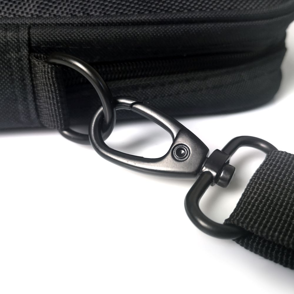 Dettaglio della chiusura di una borsa nera con moschettone e attacco.
