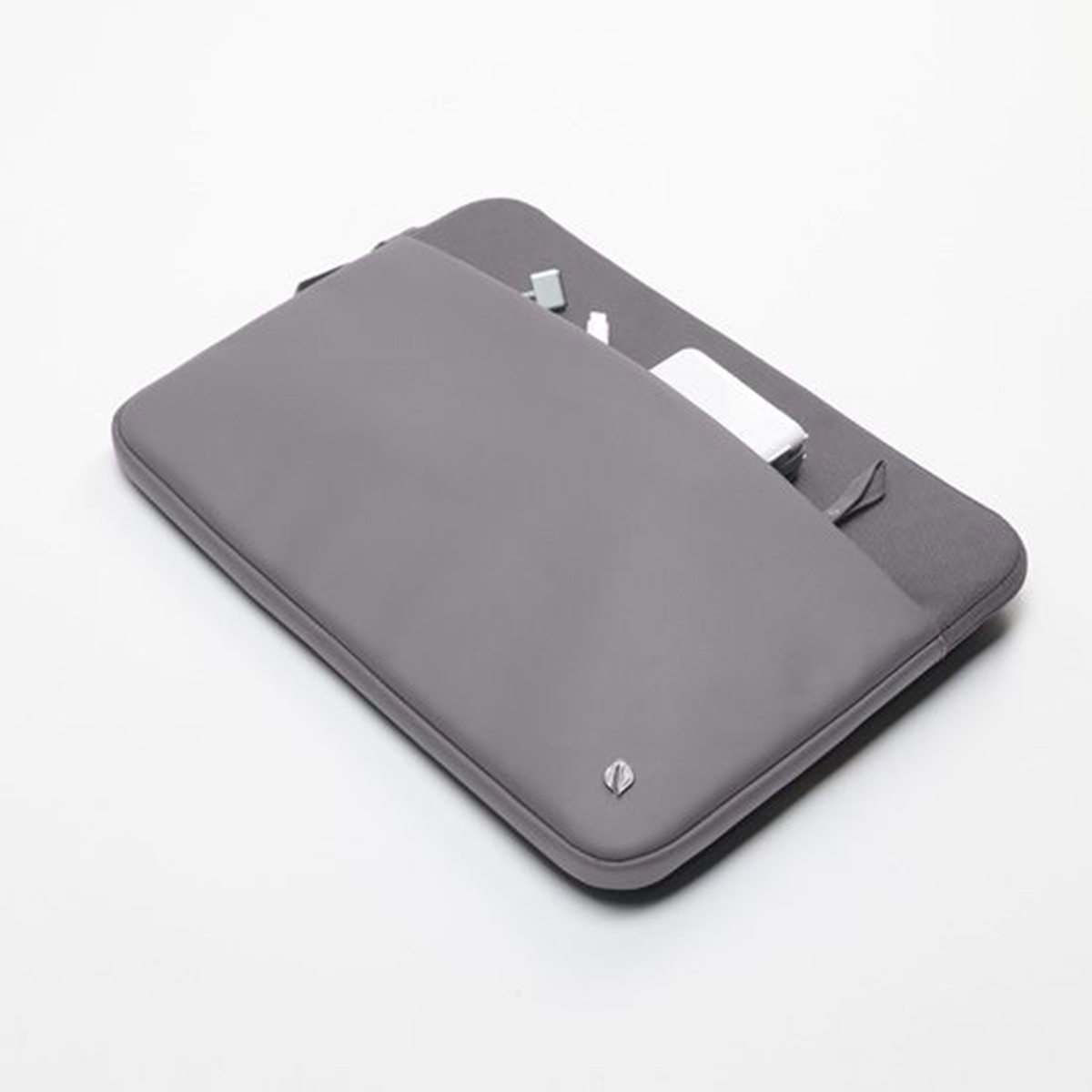 Graue Laptoptasche mit kleinem Logo und Gegenständen, die aus der Tasche herausragen. Weißer Hintergrund.