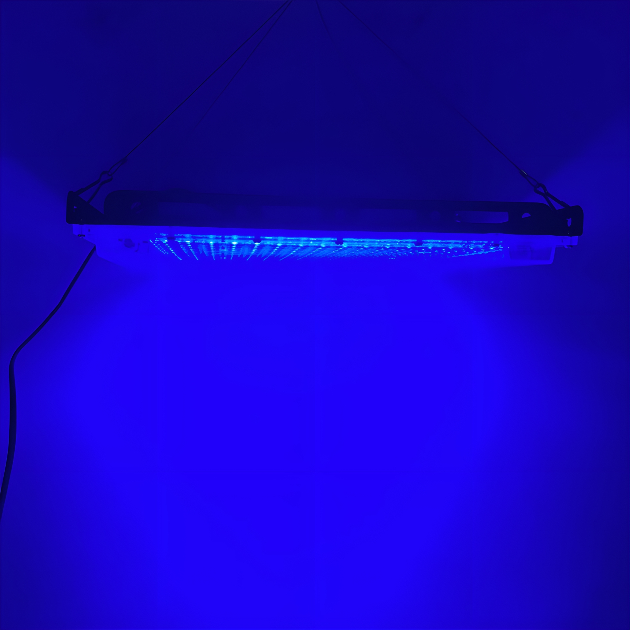 Blaue Leuchte an einer blauen Wand. Dunkler Hintergrund.