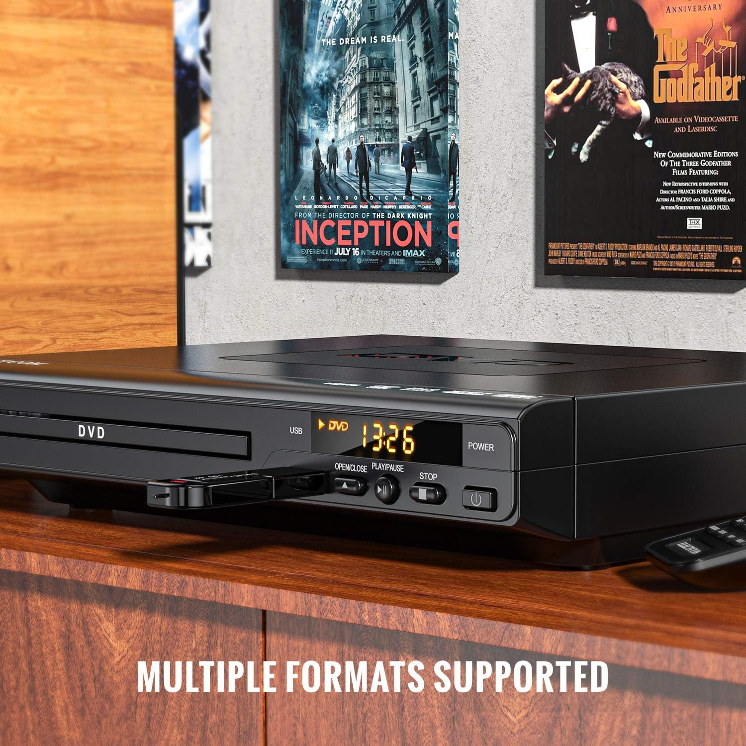 Schwarzer DVD-Player mit USB. Filmplakate sind im Hintergrund. Holztisch.