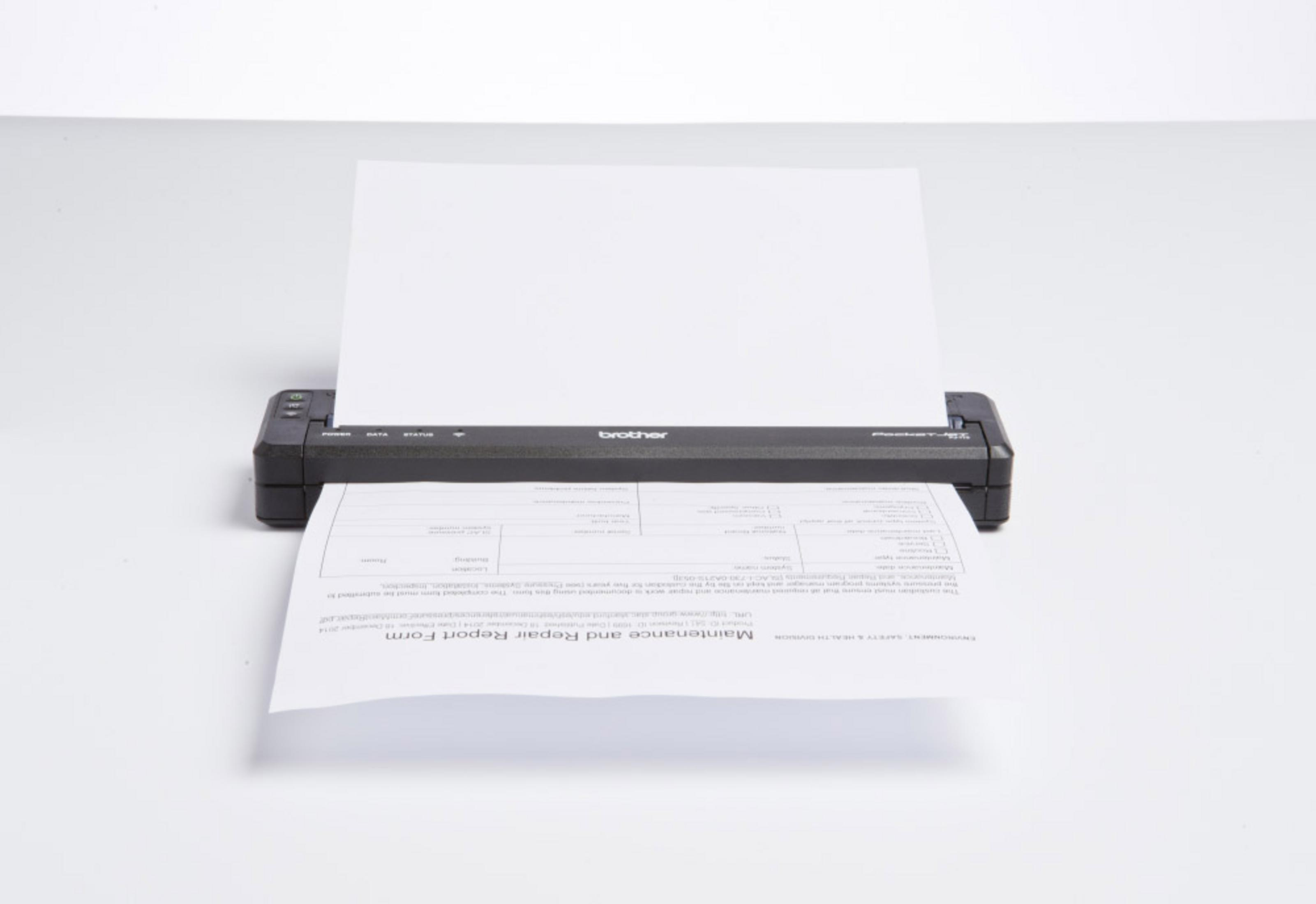 Stampante per etichette nera Brother P-touch con carta che esce, su una superficie bianca.