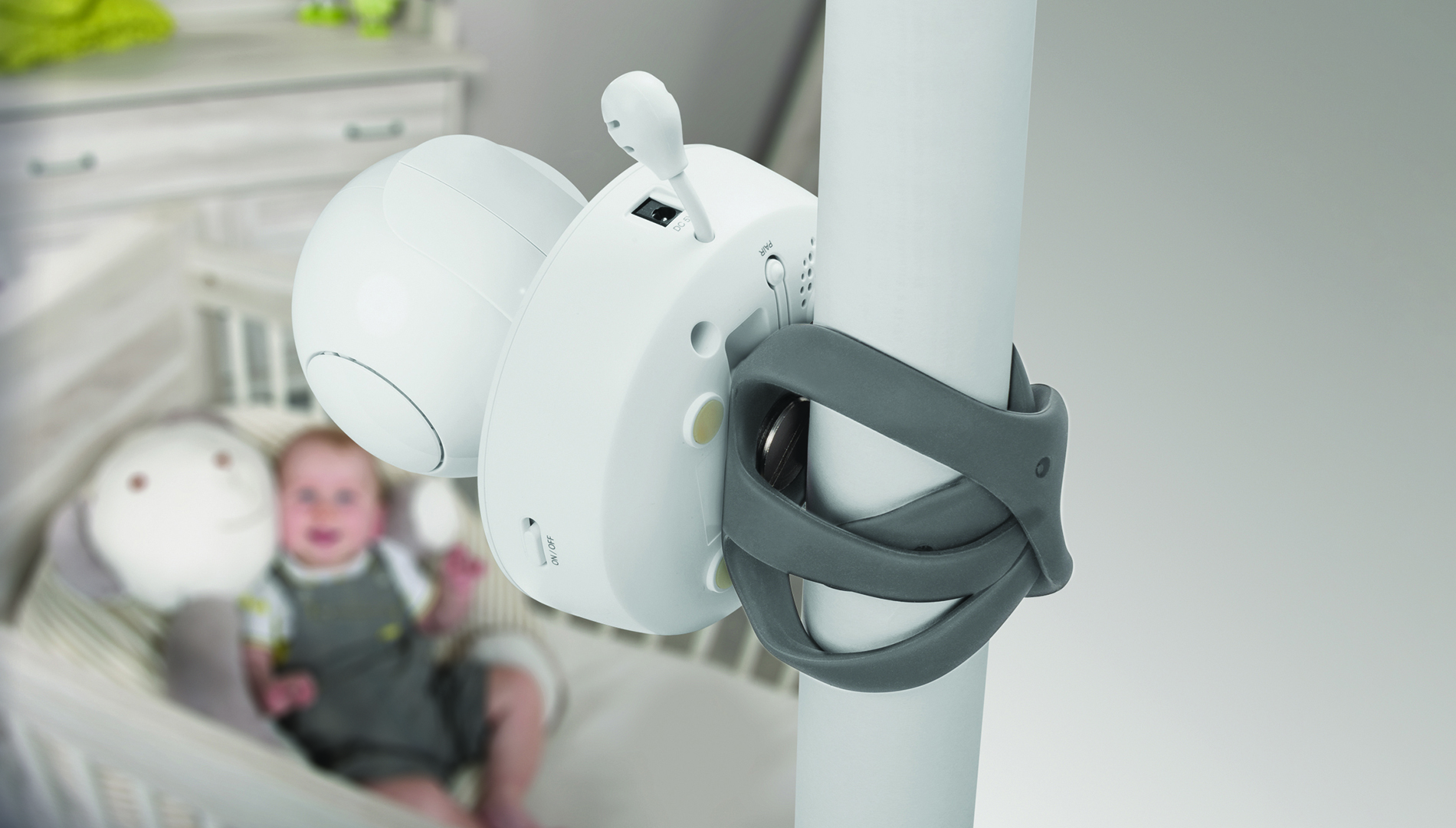 Ein Babyphone an einer Stange befestigt. Ein Baby ist im Hintergrund unscharf.