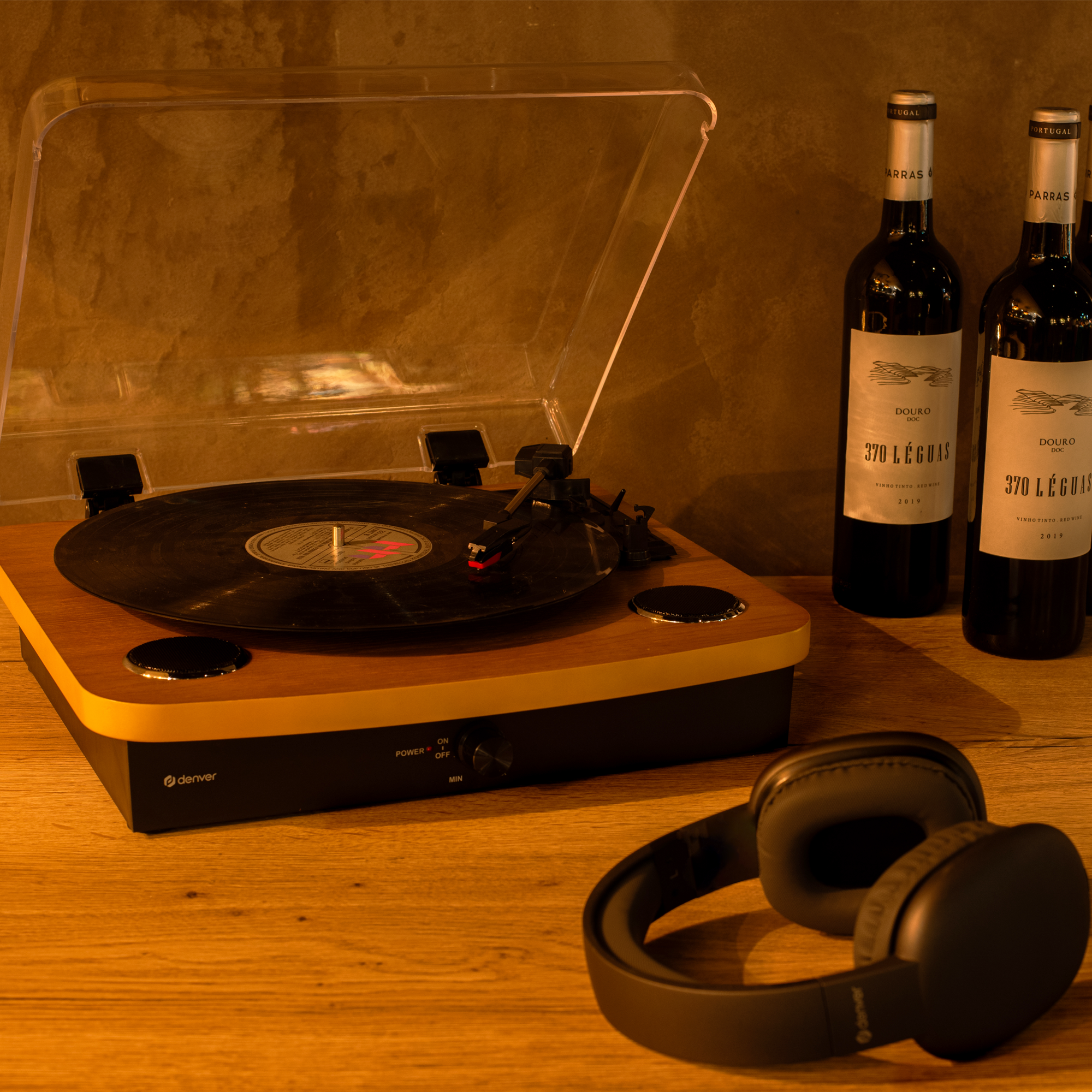 Gramofon z butelkami wina i słuchawkami na drewnianej powierzchni.