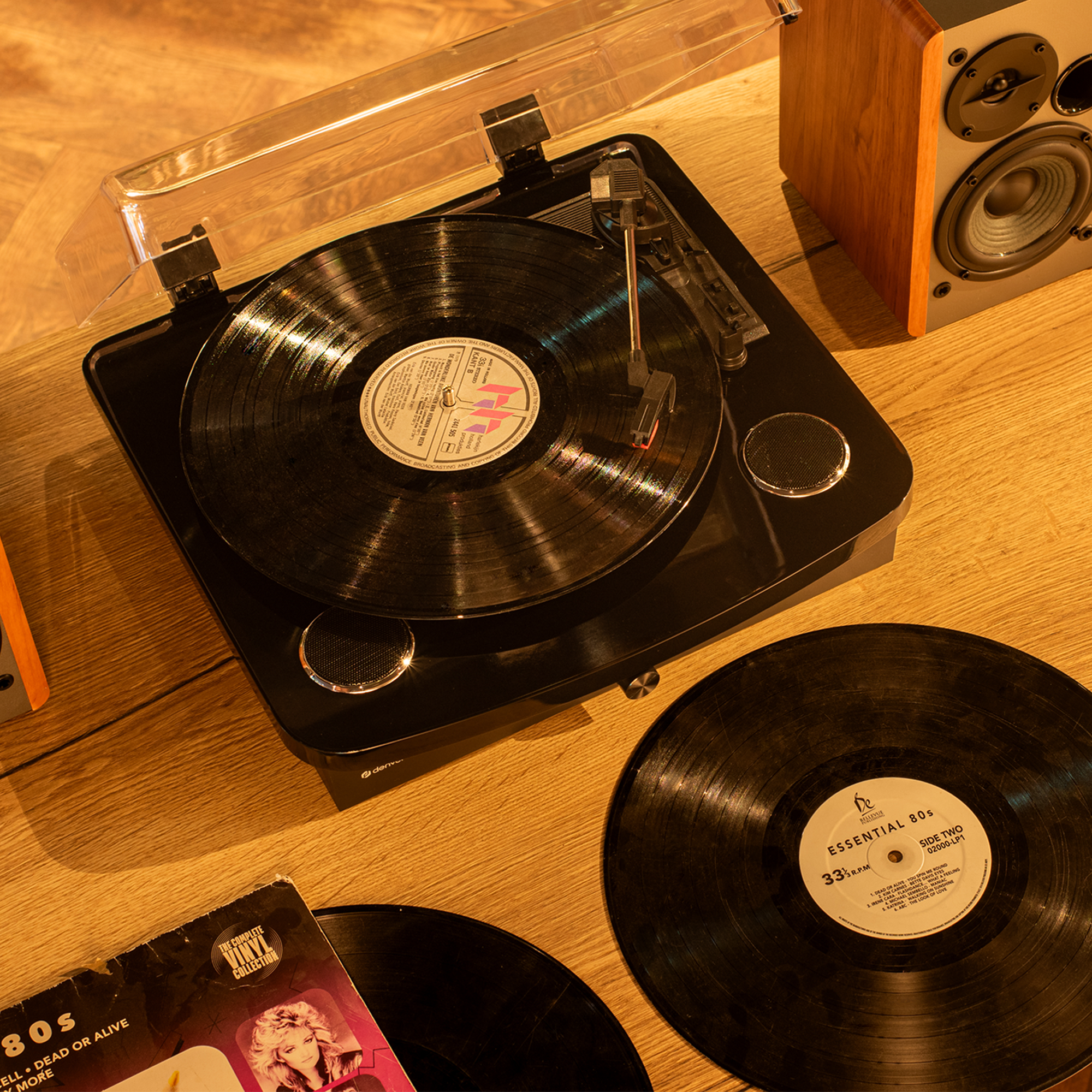 Gramofon odtwarzający płytę, z głośnikami i innymi płytami w pobliżu.