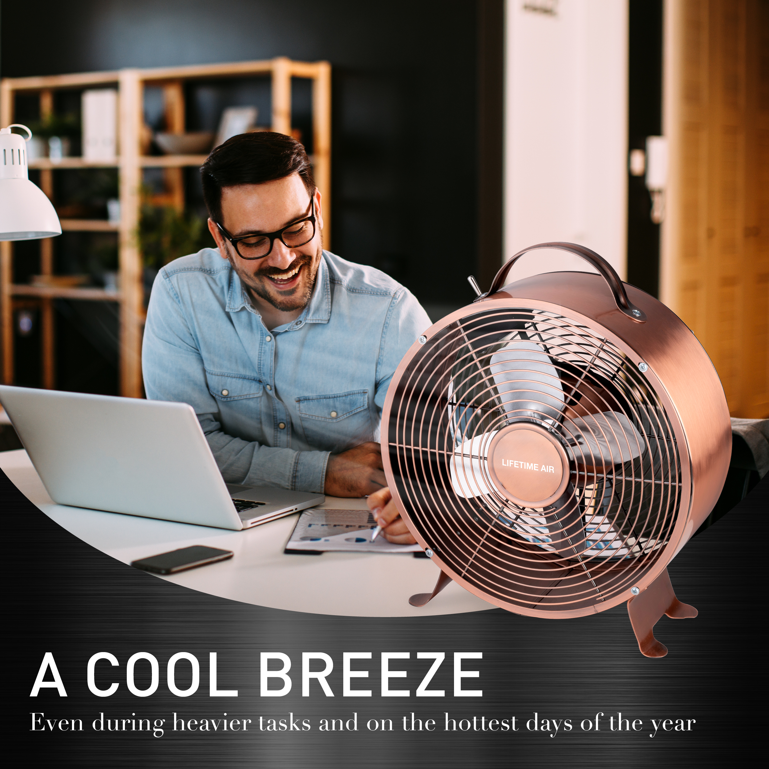Ein Mann lächelt und benutzt einen Laptop. Ein Kupferventilator steht neben ihm.