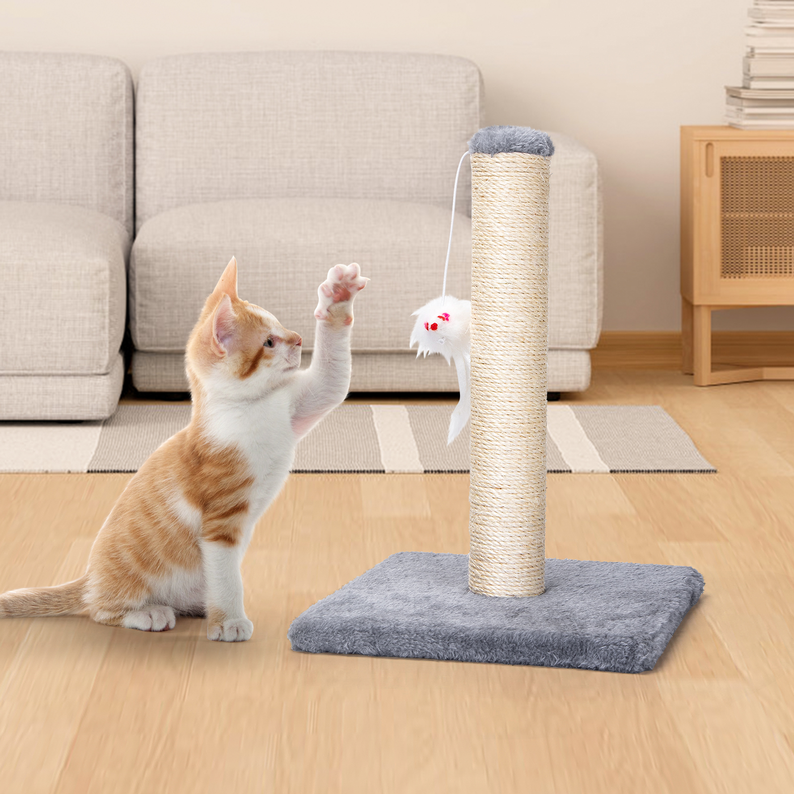 Un gatito alcanza un juguete en un rascador. El poste es beige y el gato es naranja y blanco.