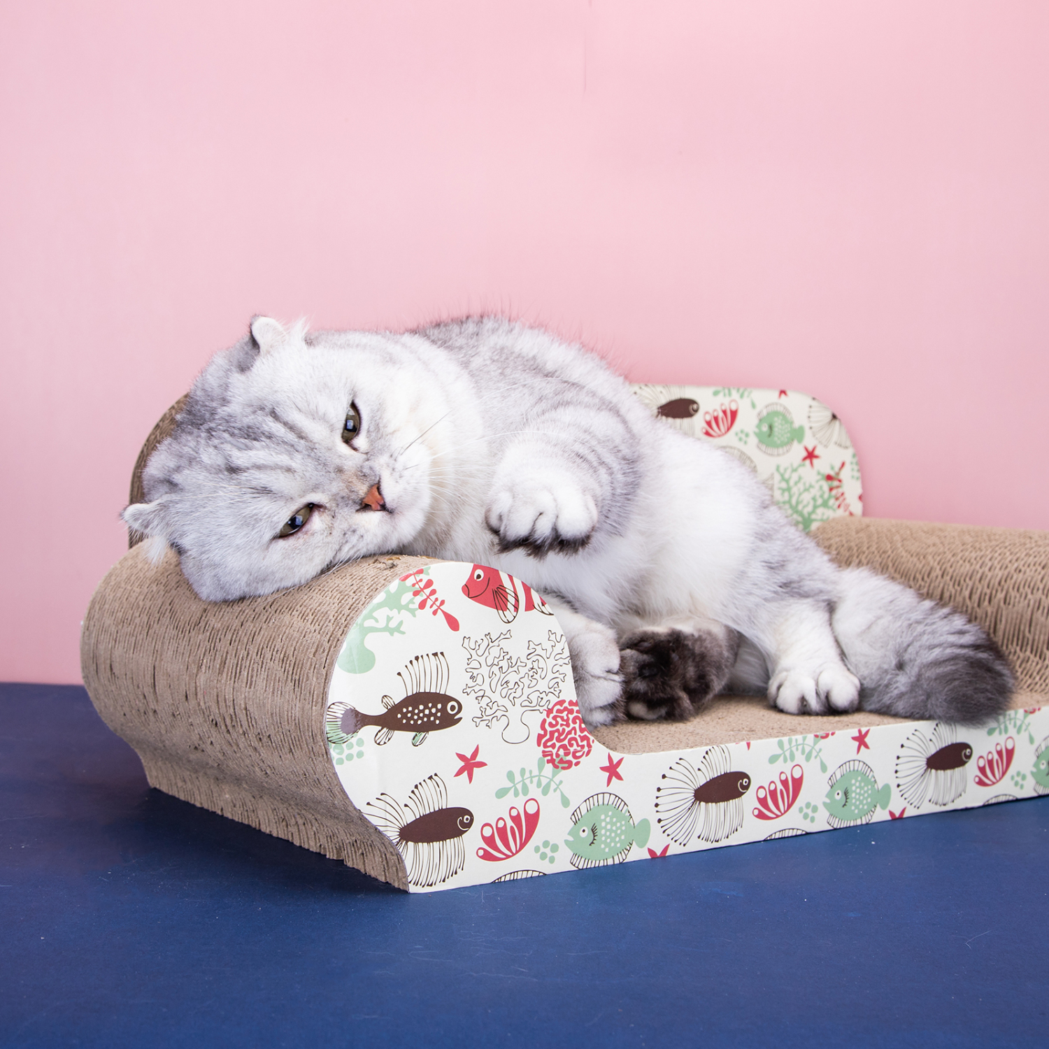 Un gato gris está acostado en un sofá para gatos. El gato descansa en un sofá estampado.