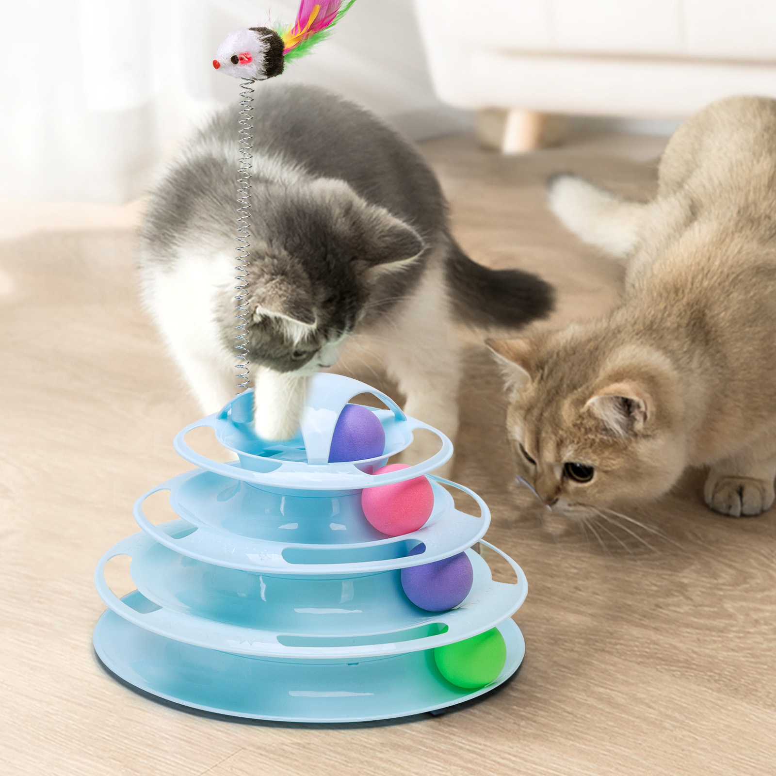 Dos gatitos jugando con un juguete. El juguete es una torre azul con bolas de colores.