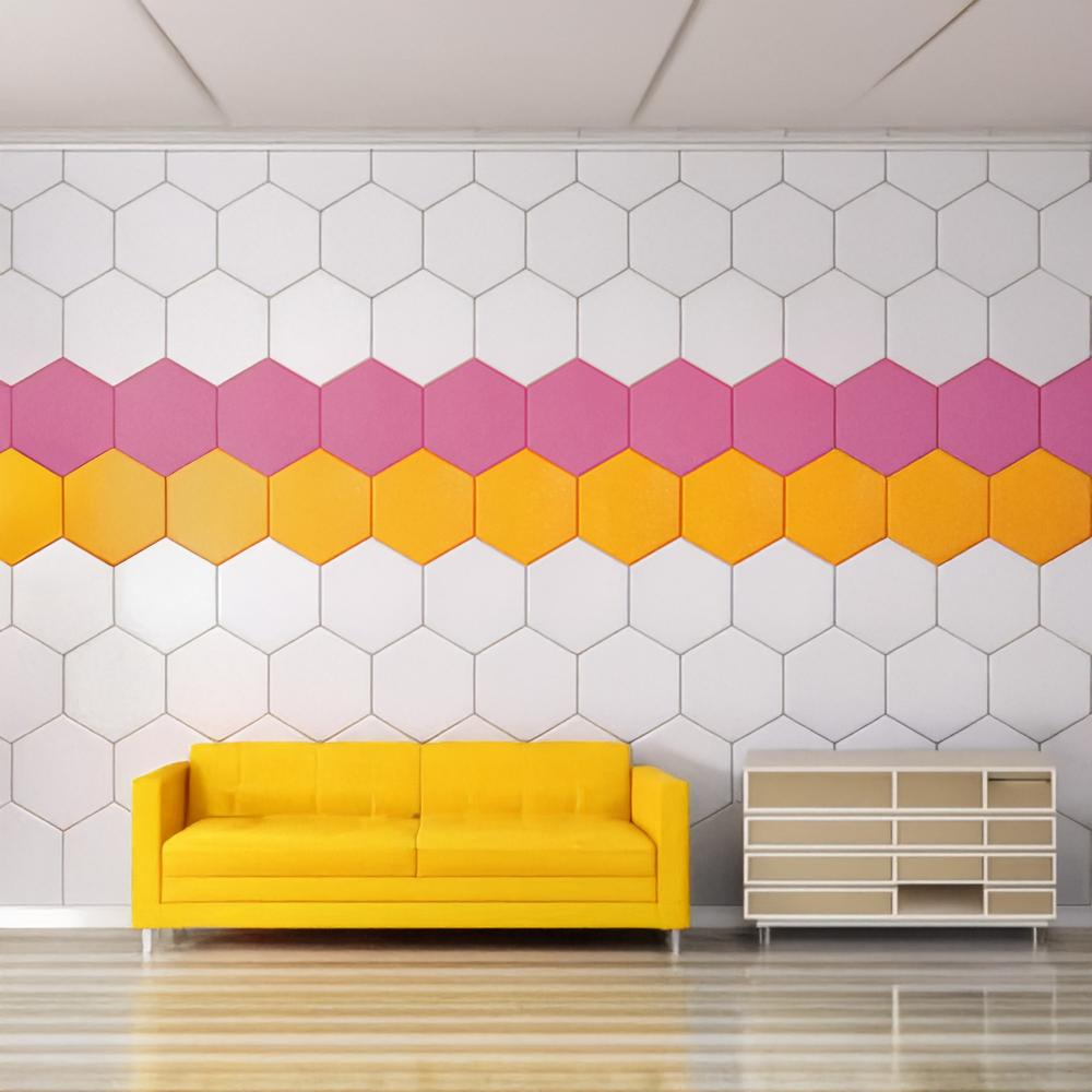 Habitación con sofá amarillo, pared hexagonal blanca y rosa, y mueble marrón claro.