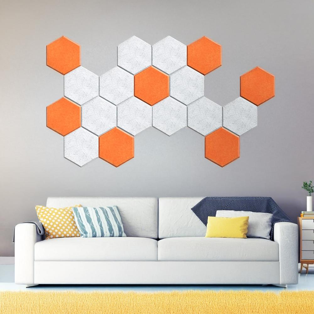 Sofá blanco con paneles de sonido hexagonales naranjas y blancos en la pared.