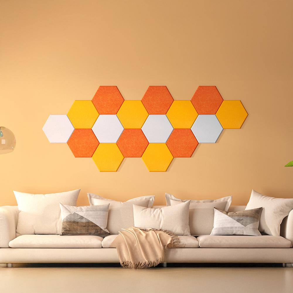 Una pared decorada con paneles en forma de panal en naranja, amarillo y blanco. Un sofá debajo.