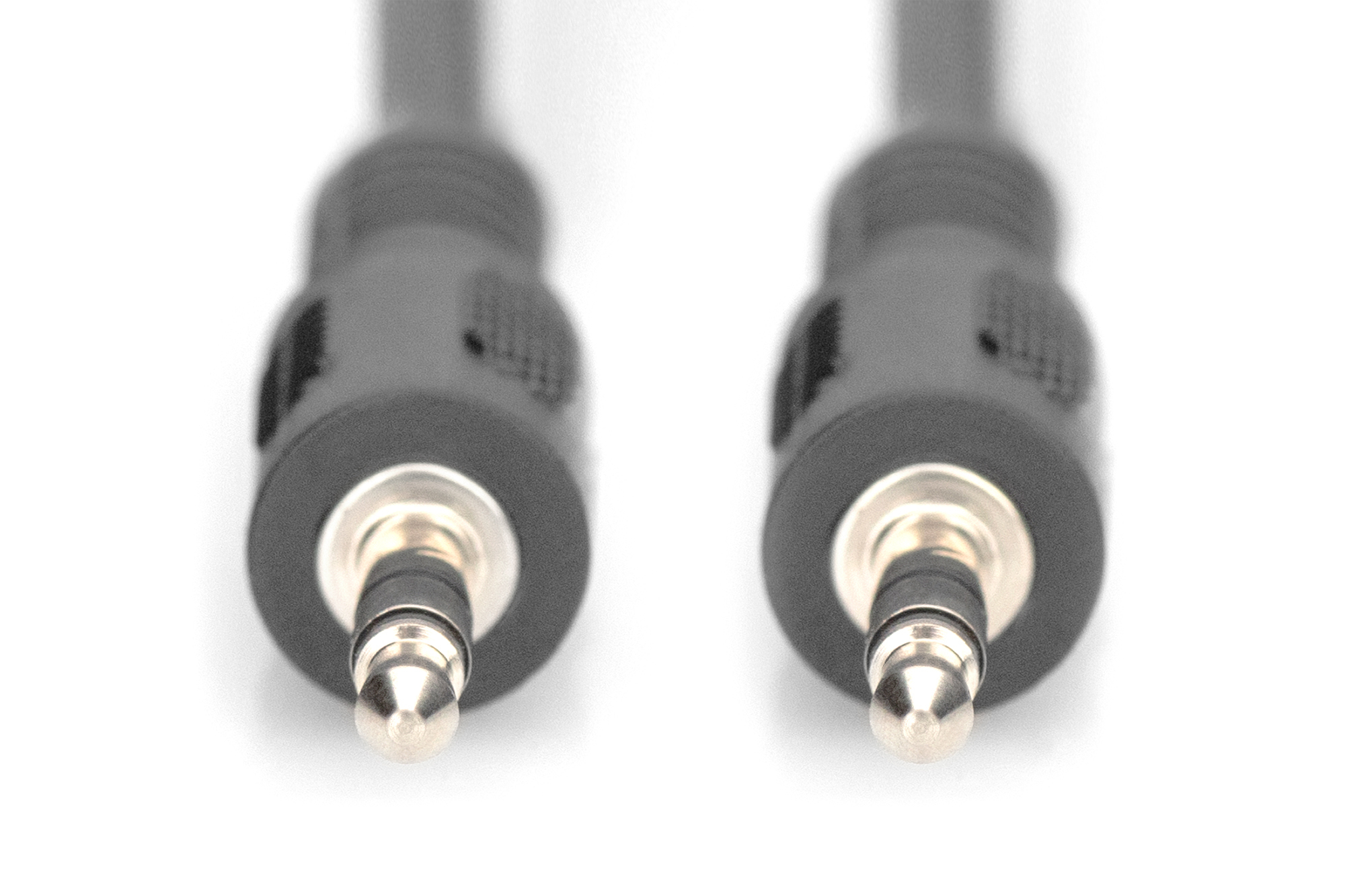 Deux prises audio 3,5 mm noires sur fond blanc. Mise au point sur les pointes.