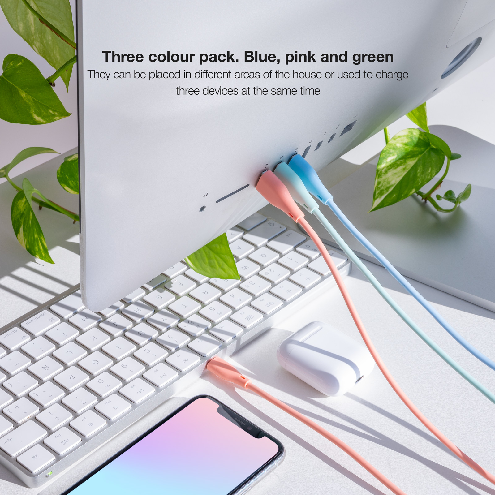 Drei Ladekabel: blau, rosa und grün, an einen Computer und ein Telefon angeschlossen, mit einem weißen Kopfhörer-Etui.