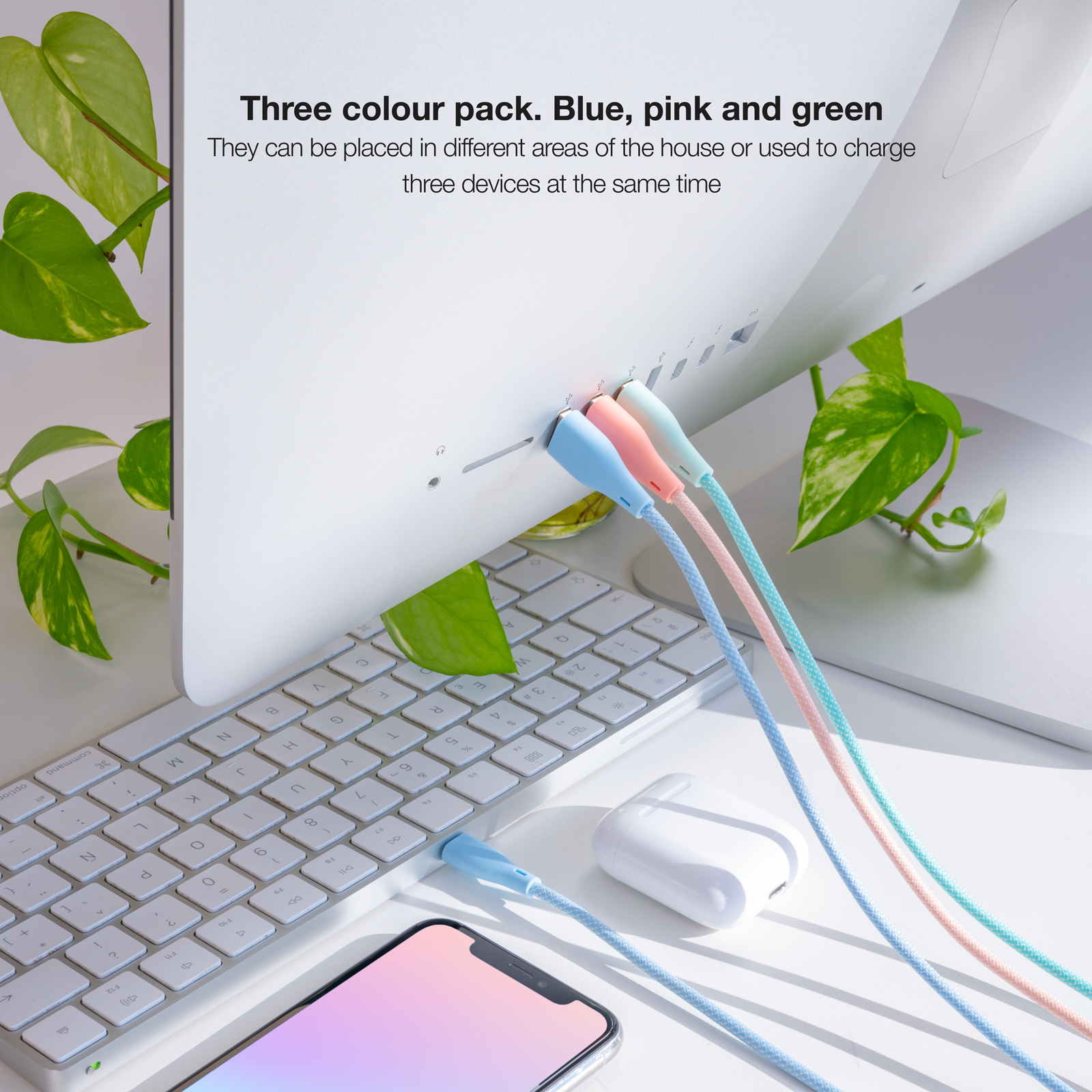 Close-up van een computer met drie oplaadkabels: blauw, roze en groen. Een telefoon en oortelefoons zijn ook zichtbaar.