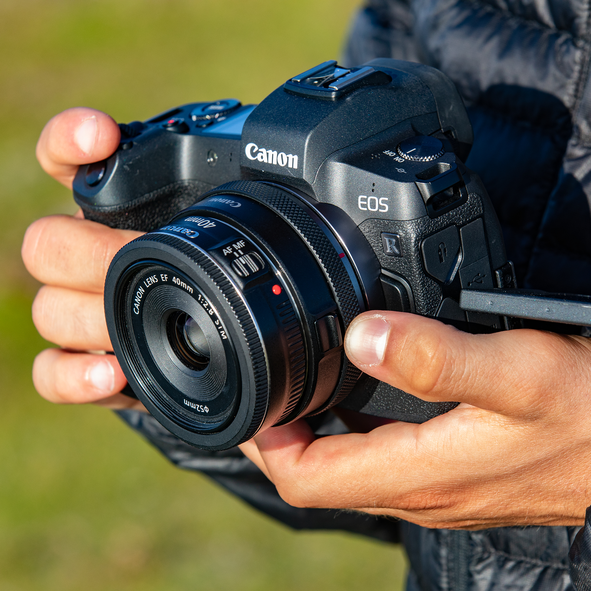 Eine Person hält eine Canon-Kamera mit einem 40-mm-Objektiv.