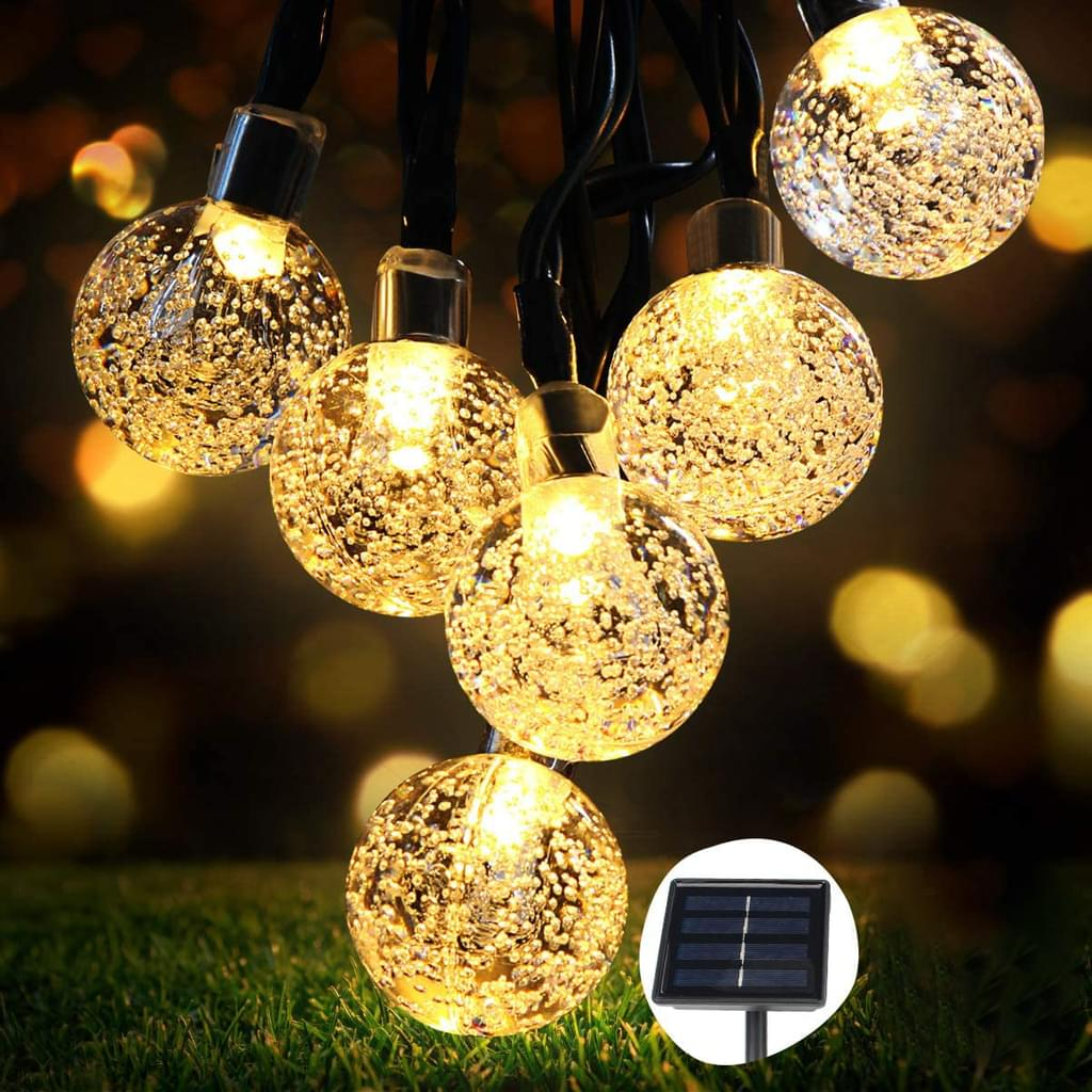 Lichterkette mit runden, klaren, blasenartigen Kugeln, die warm leuchten. Solarpanel sichtbar.