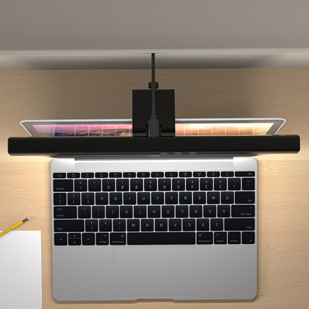 Laptop mit Tastatur, schwarzes Licht darüber. Holzschreibtisch.