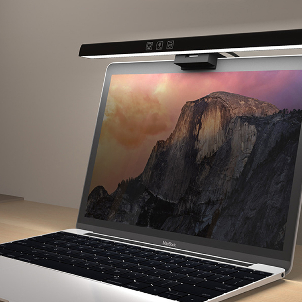 Ein Laptop mit einer Schreibtischlampe darüber. Die Lampe ist schwarz und beleuchtet die Tastatur.