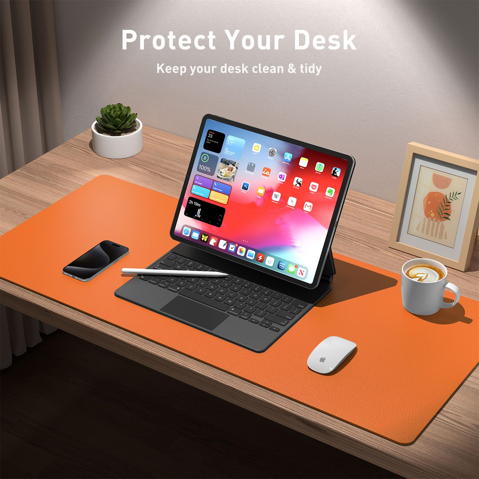 Eine orangefarbene Schreibtischunterlage mit Tablet, Telefon und Zubehör. Ein gerahmtes Bild ist auch vorhanden.