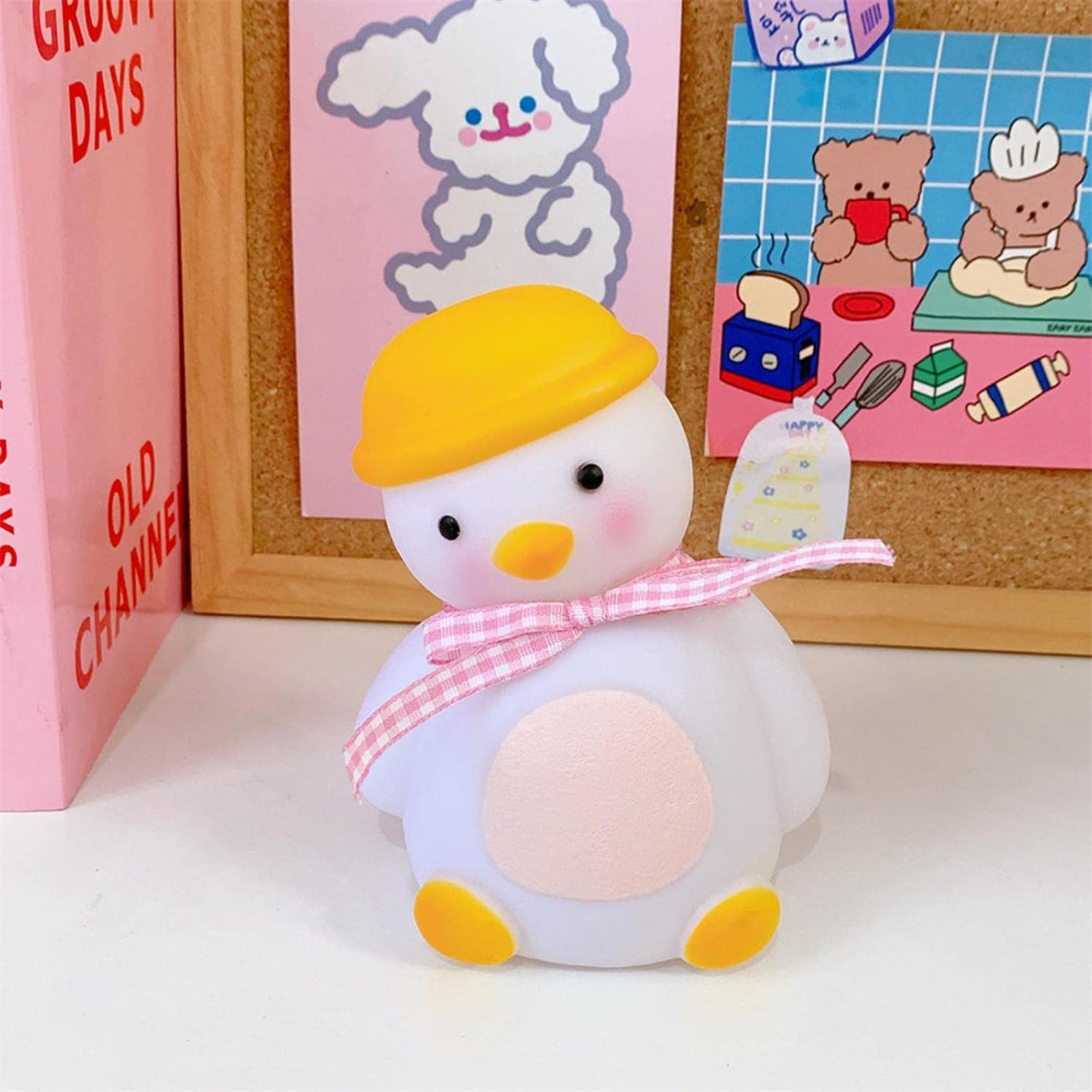 Eine cartoonartige ente Lampe mit gelbem Hut und rosa Schleife steht vor einer Holztafel.